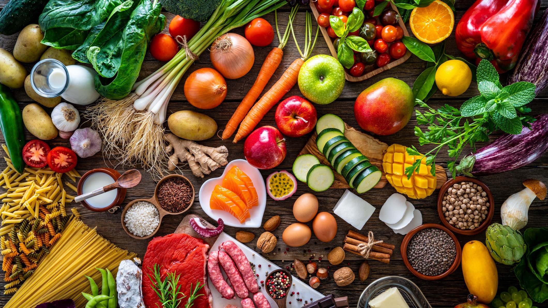 Gran variedad de alimentos crudos sobre una mesa de madera