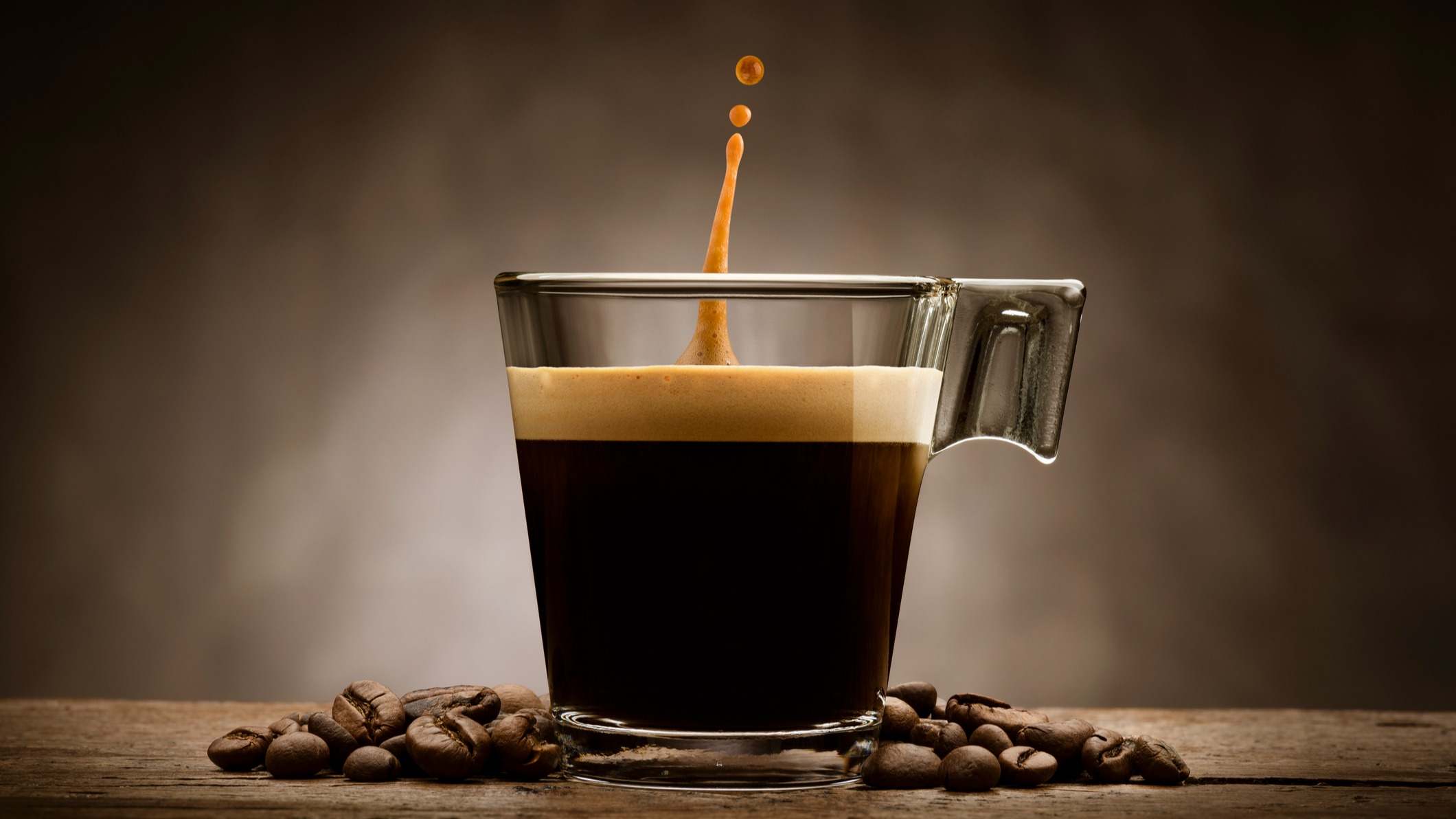 Taza de café rodeada por granos de café sobre un fondo marrón