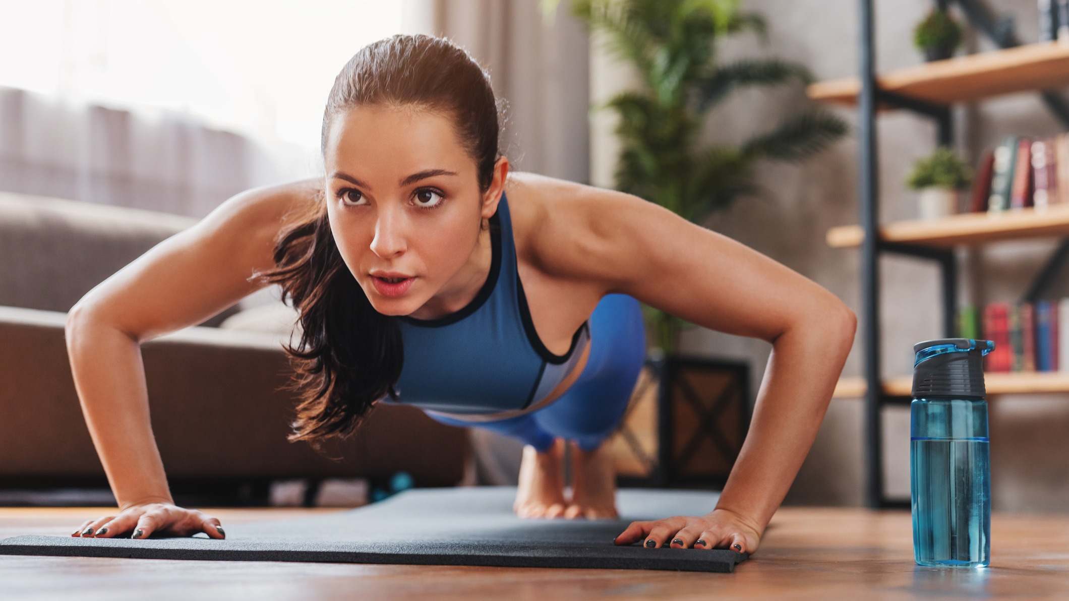 Mujer haciendo flexiones en el salón de casa con una esterilla sobre el suelo