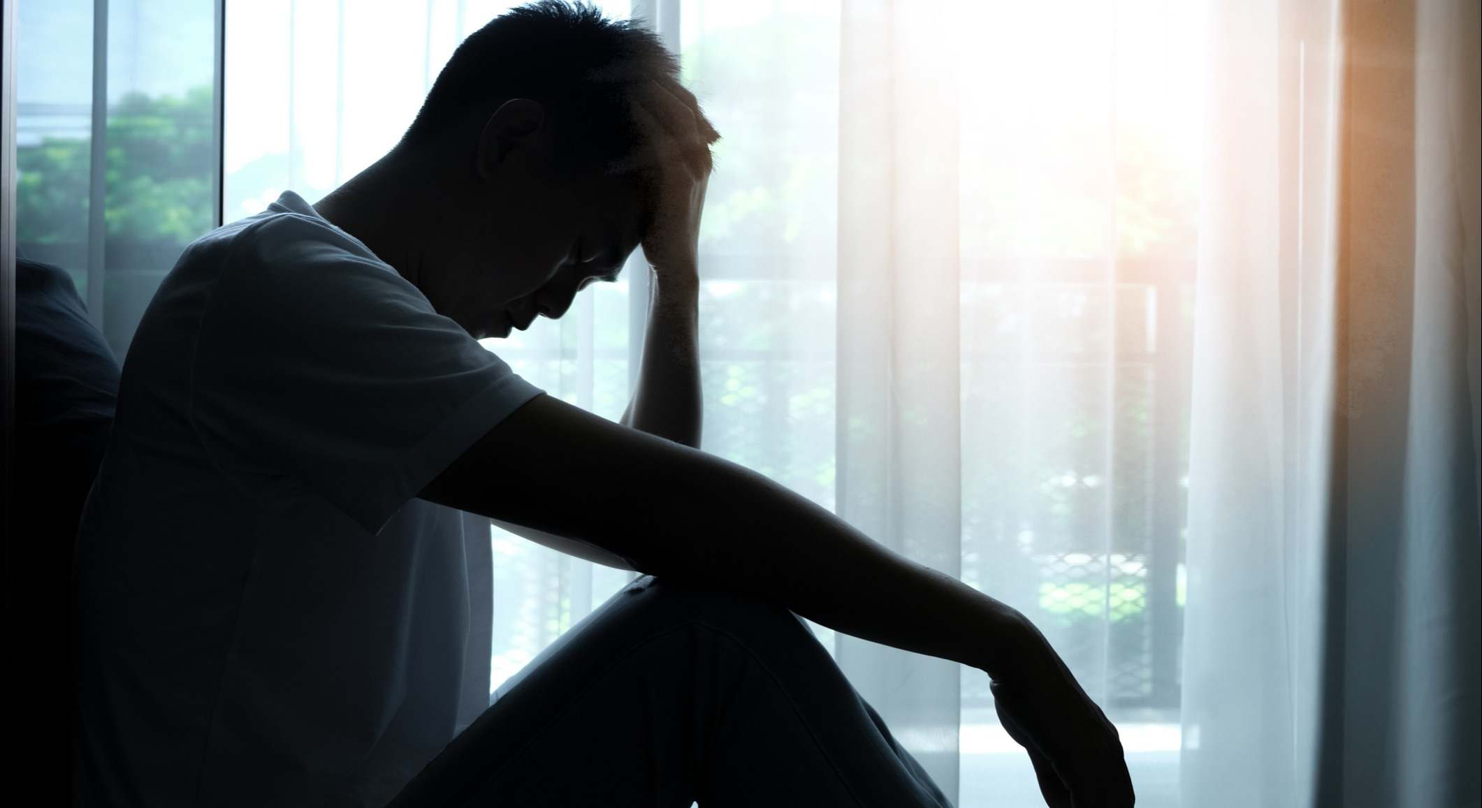 Hombre cabizbajo sentado en una habitación