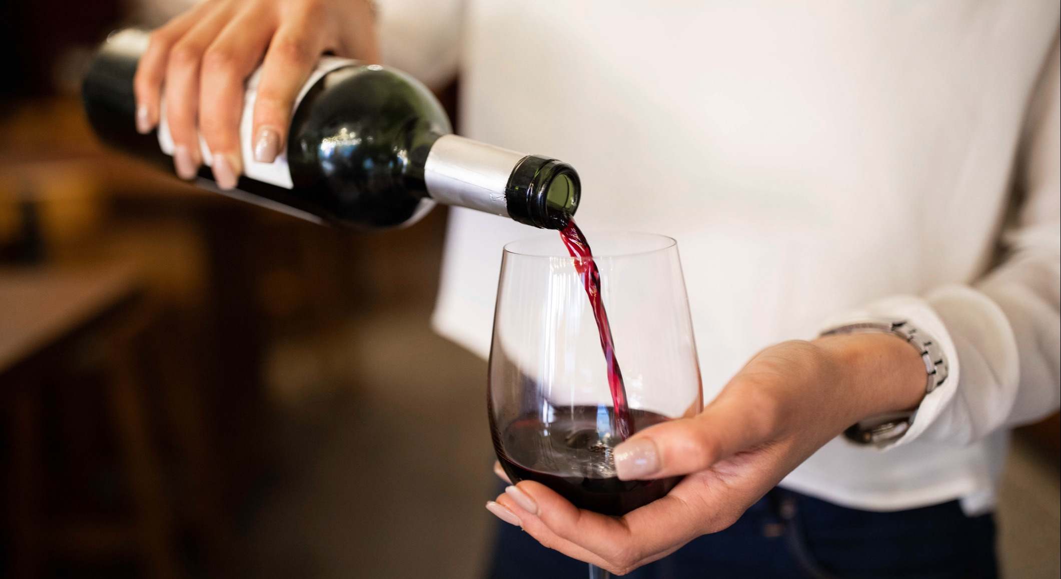 Mujer sirviendo vino tinto en una bodega