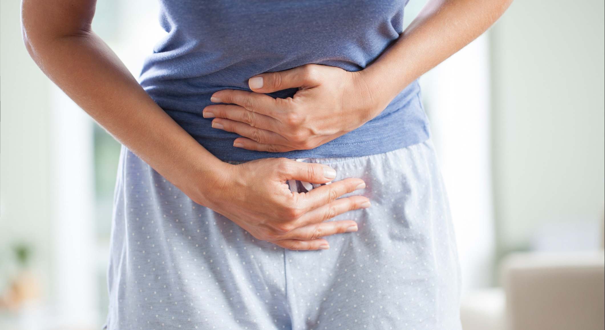 Mujer quejándose de dolor con las manos en el abdomen