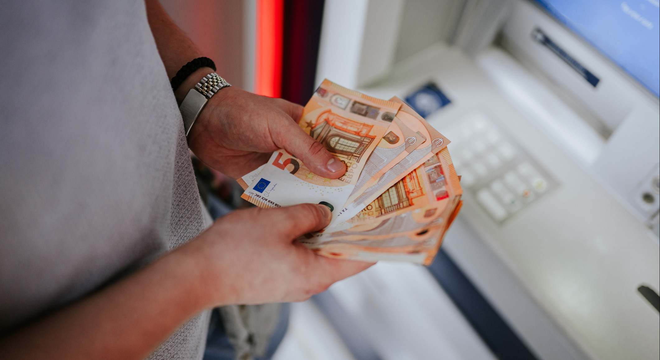 Una persona sostiene billetes de euro en un cajero