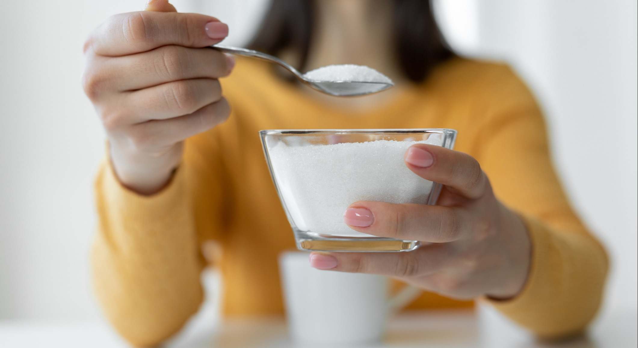 Mujer agregando azúcar refinada a la taza de café