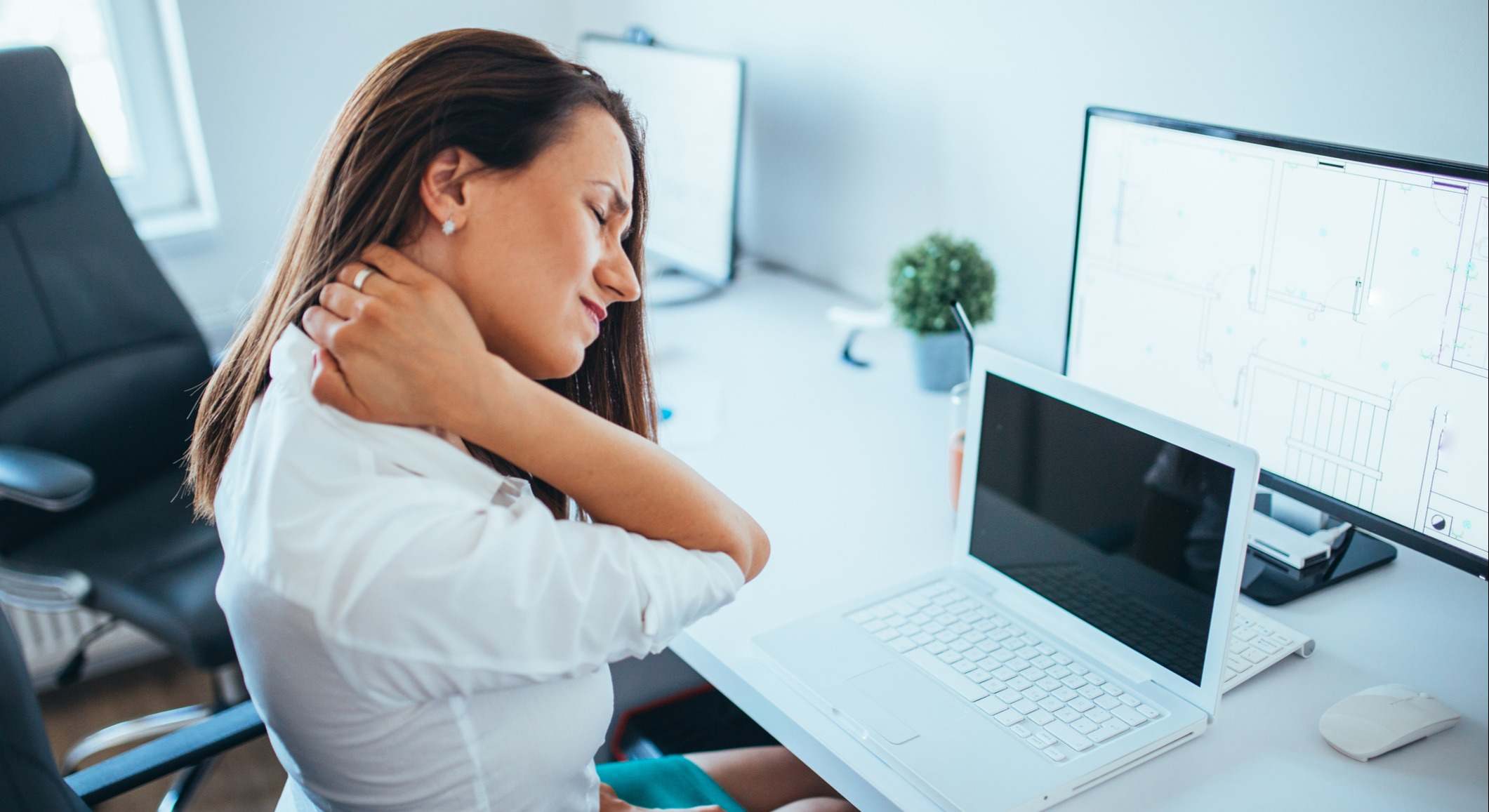 Mujer trabajando con dolor en el cuello en su puesto de trabajo