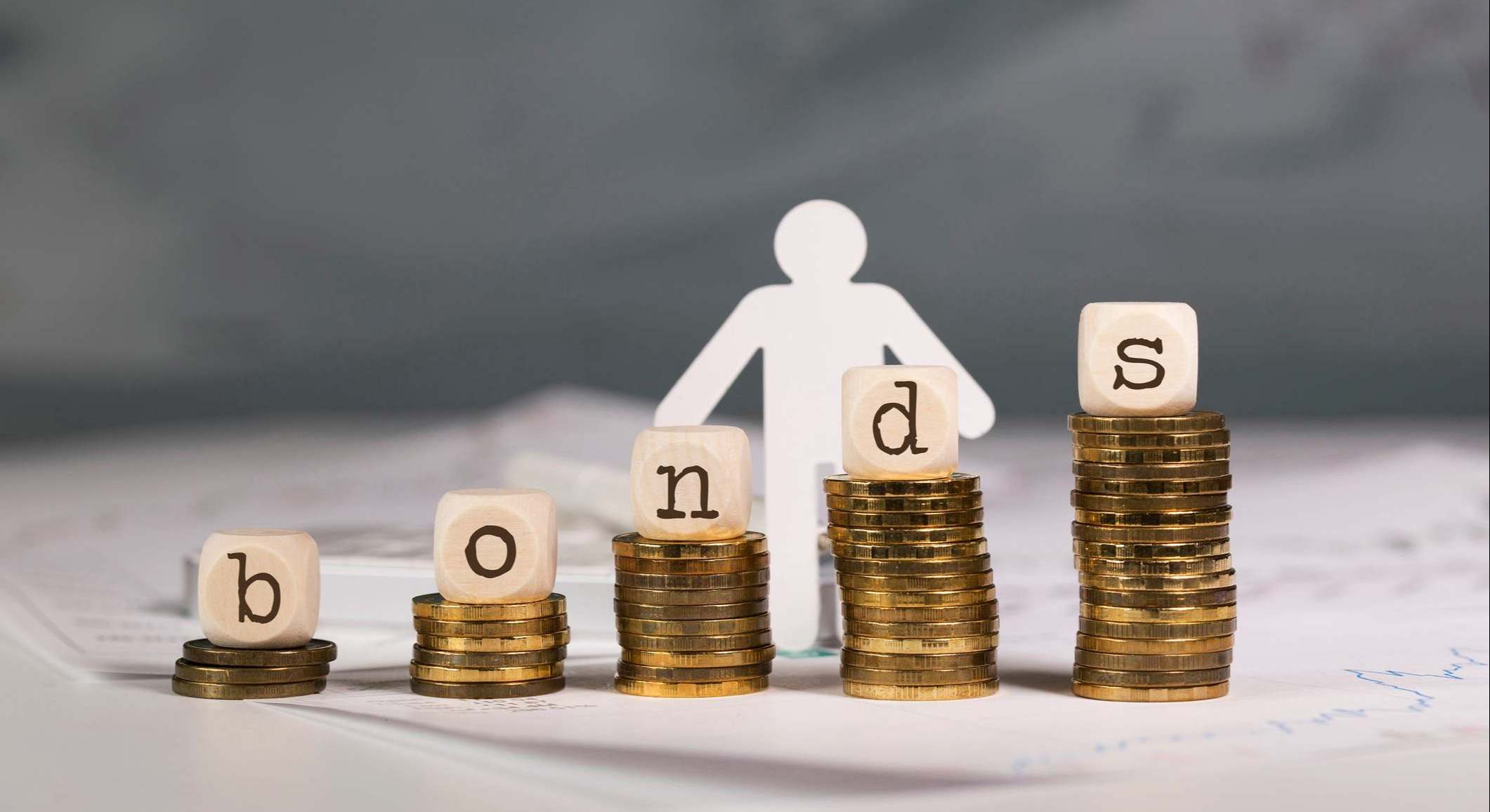 Letras de la palabra bonds encima de columnas ascendentes de monedas