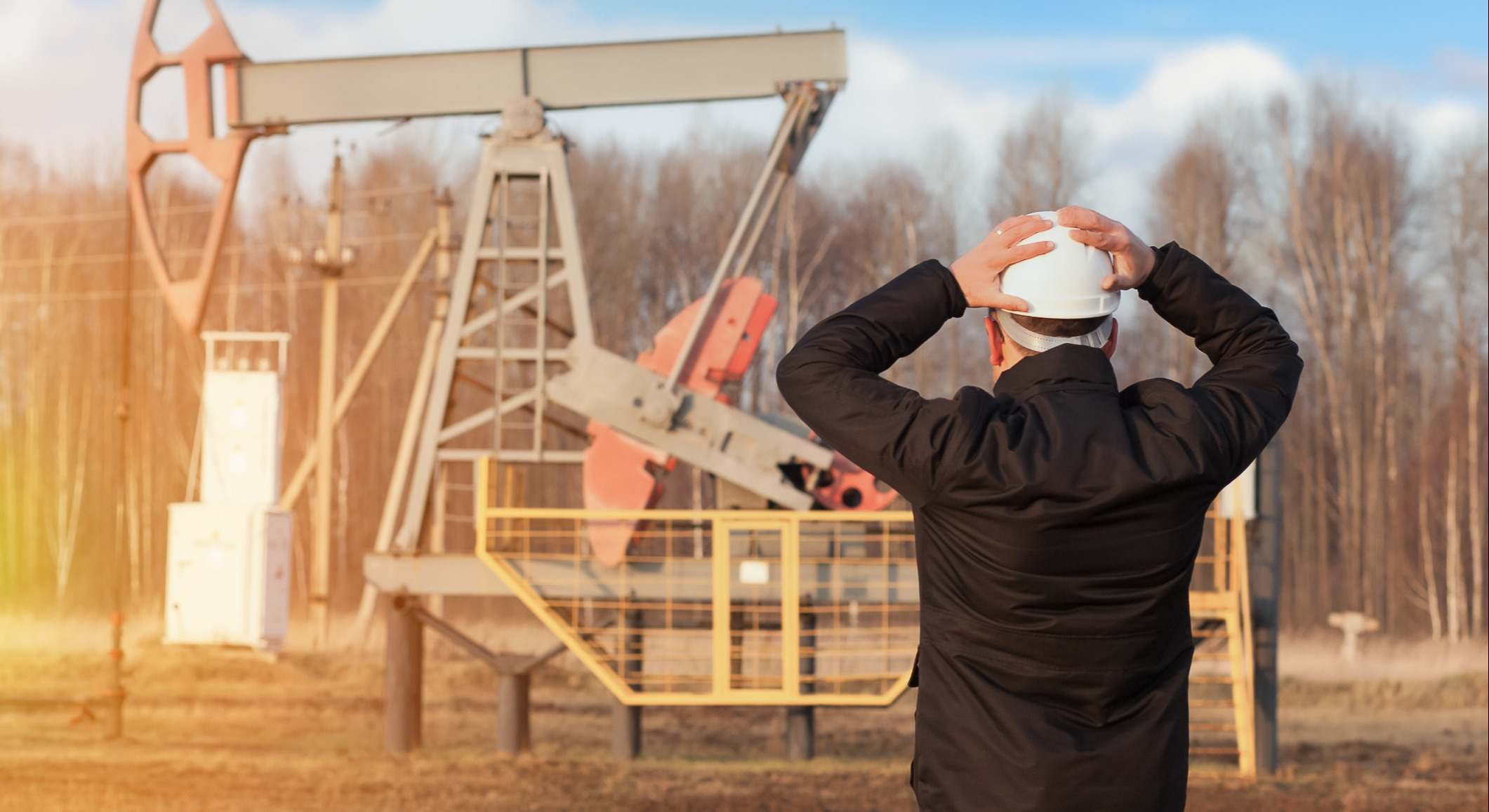 Un hombre se lleva las manos a la cabeza delante de un pozo de petróleo