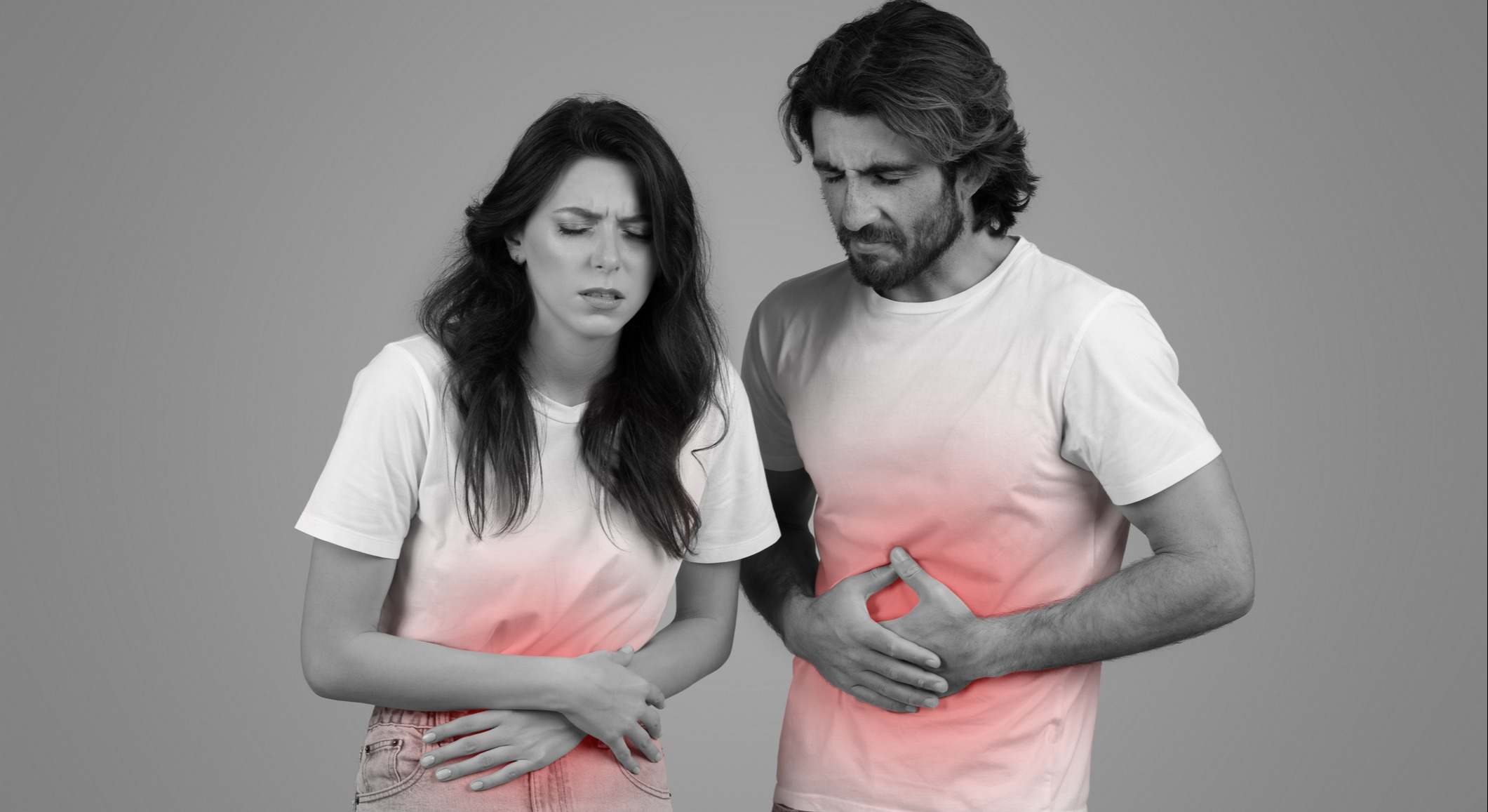 Una imagen monocromática de un hombre y una mujer con camisetas blancas, ambos con las manos en el estómago