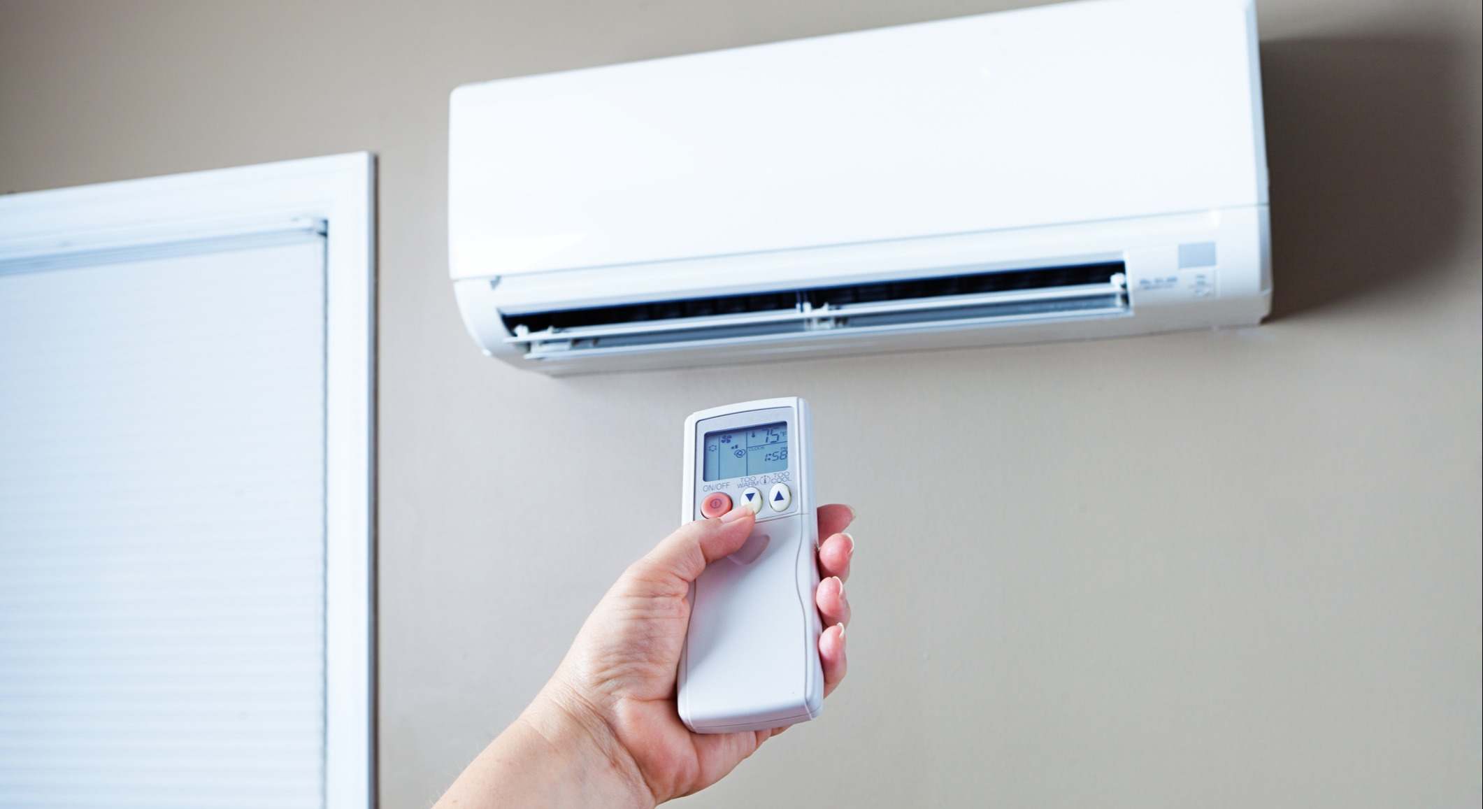 Persona manejando el aire acondicionado de una casa con un mando