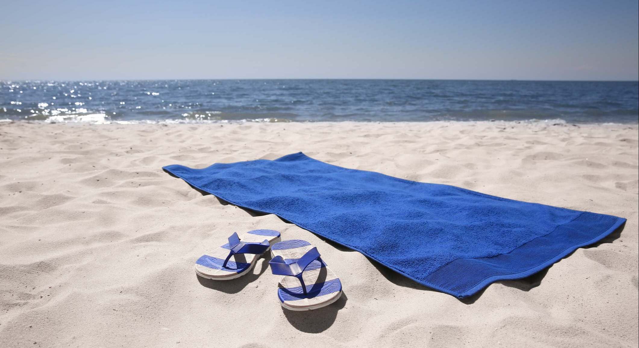 Toalla y chancletas en la arena de playa