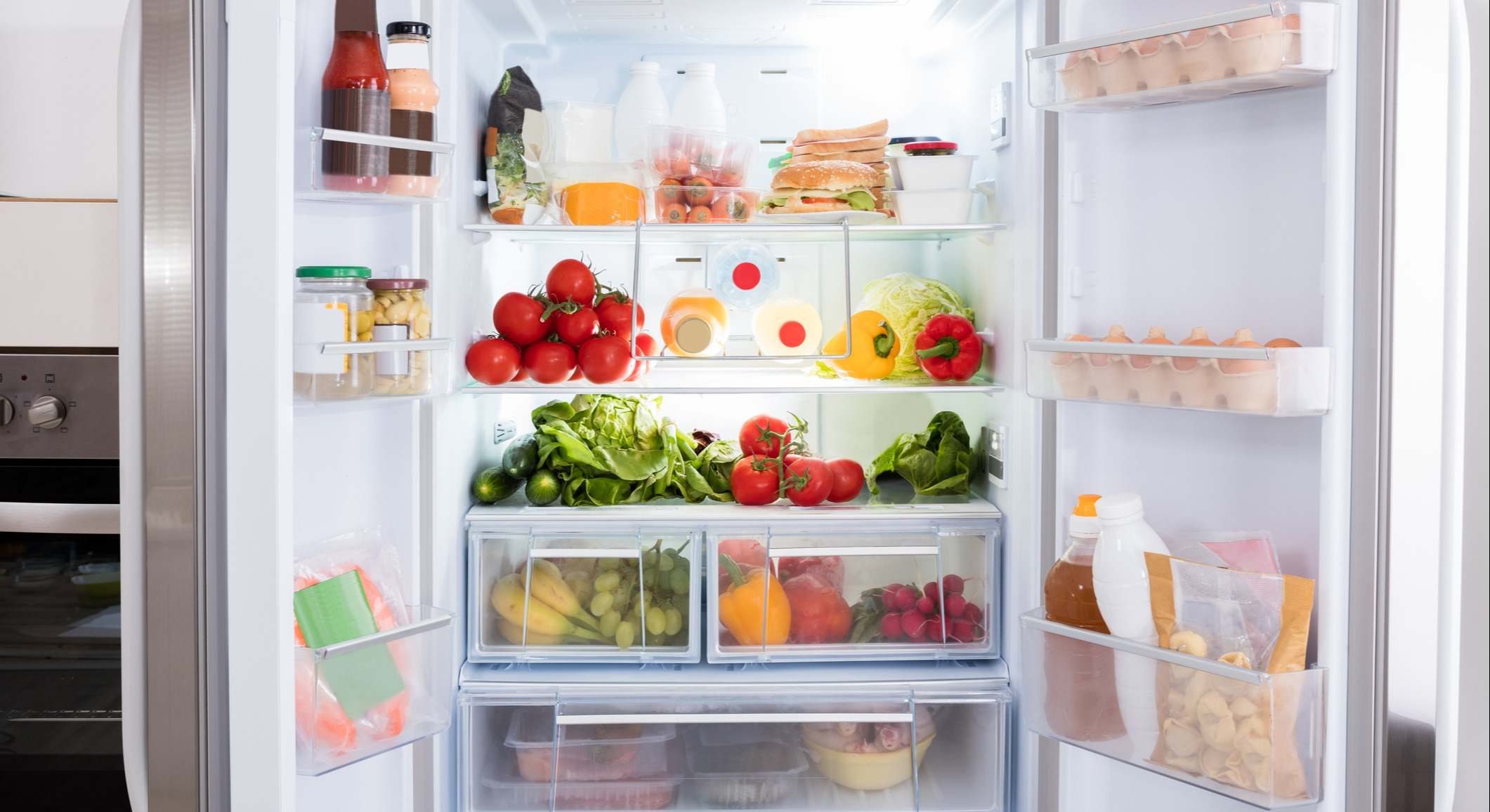 Nevera con las puertas abiertas con alimentos en su interior