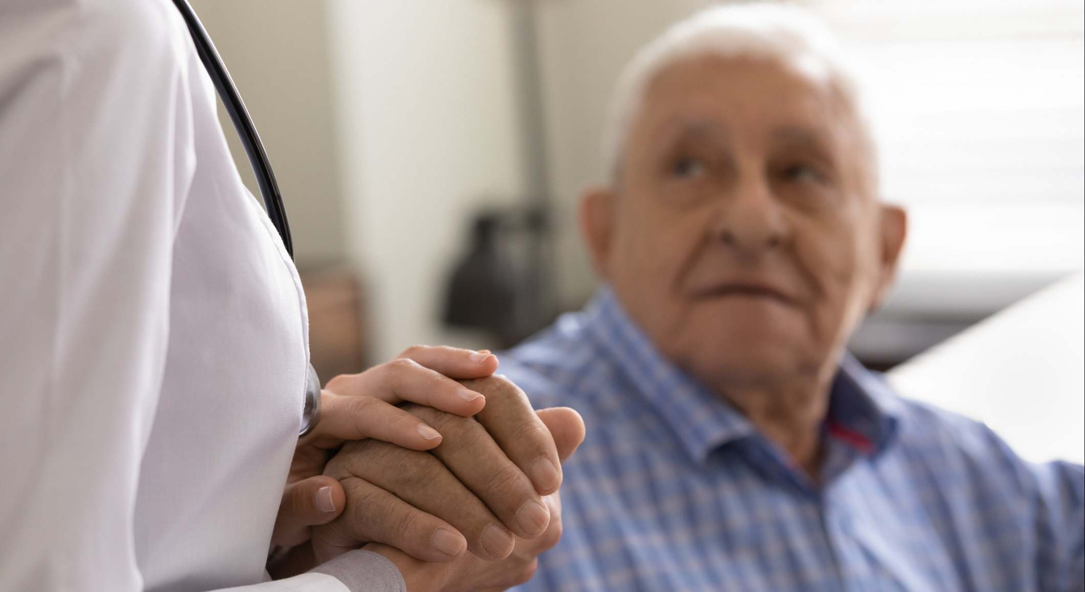 Enfermera dándole la mano a un paciente mayor
