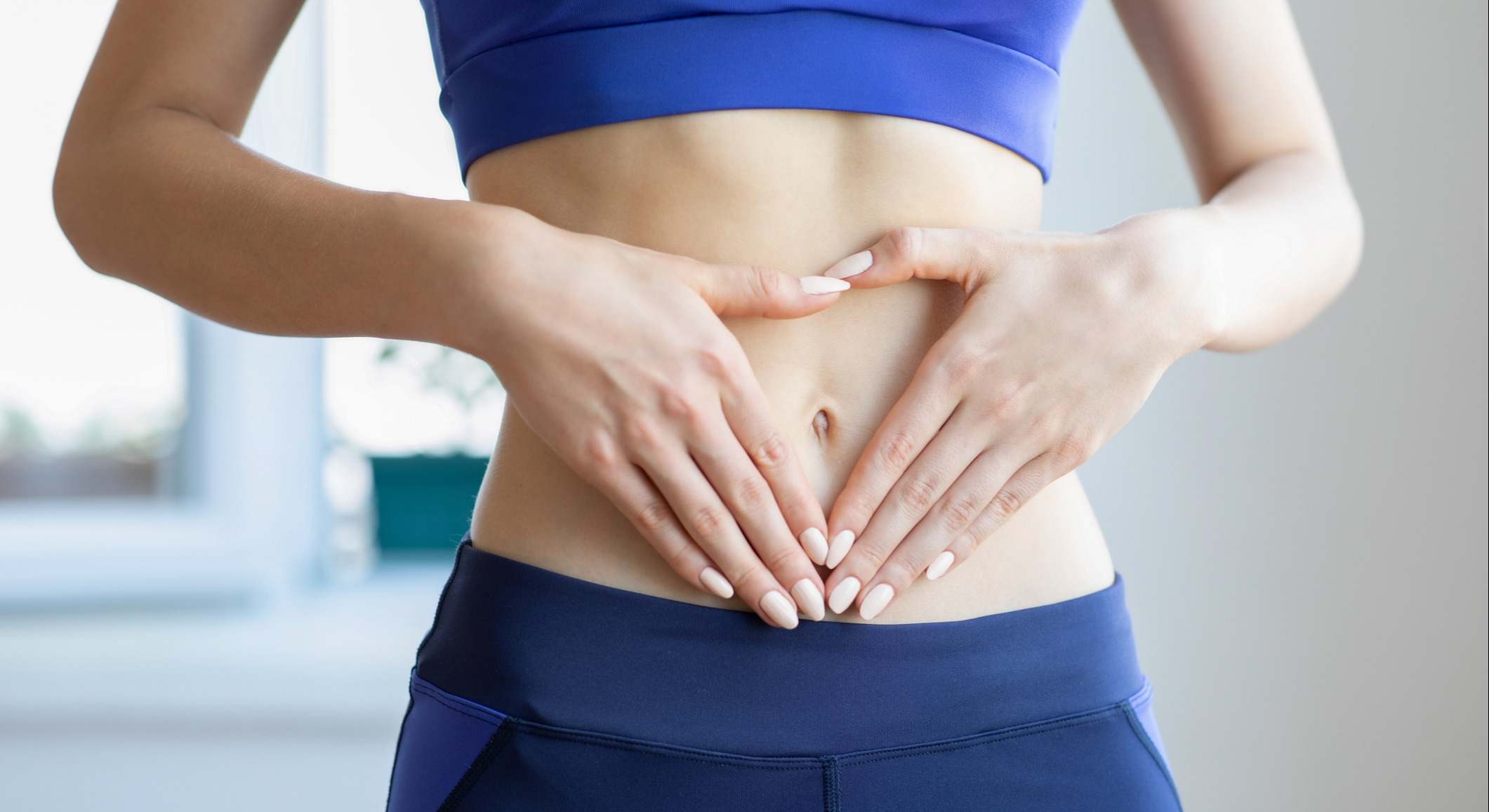 Mujer con las manos sobre el vientre formando un triángulo