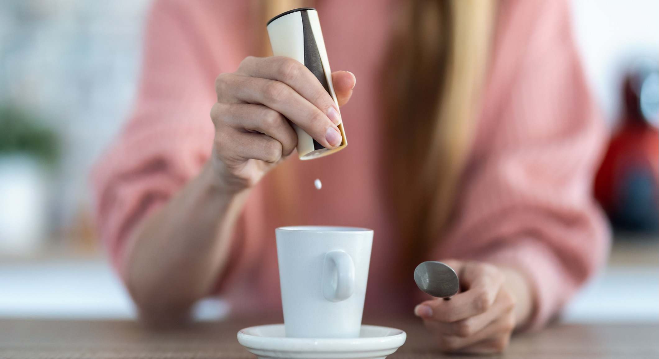 Mujer echando pastillas de sacarina en la taza de café