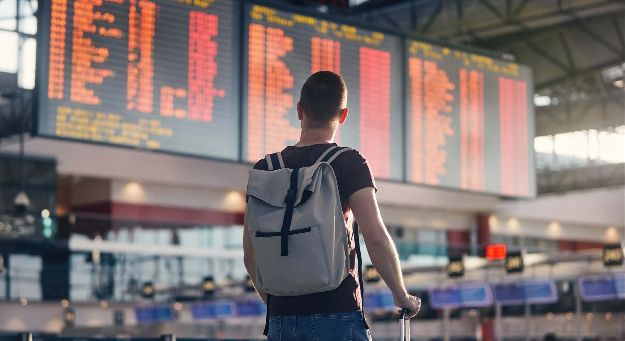 Joven con maleta y mochila en una estación de tren