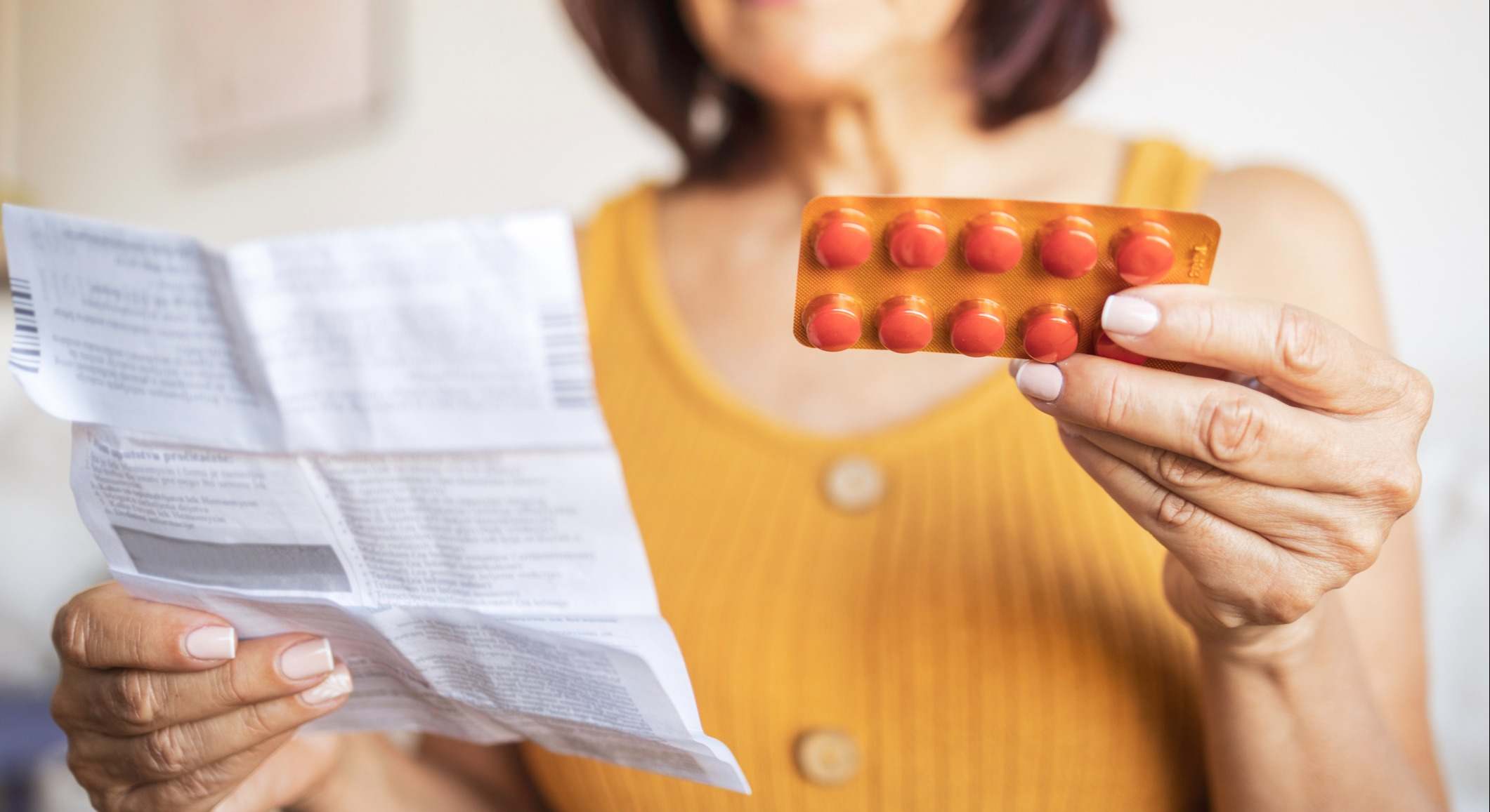 Primer plano de una mujer revisando el prospecto de información para el paciente para su medicamento