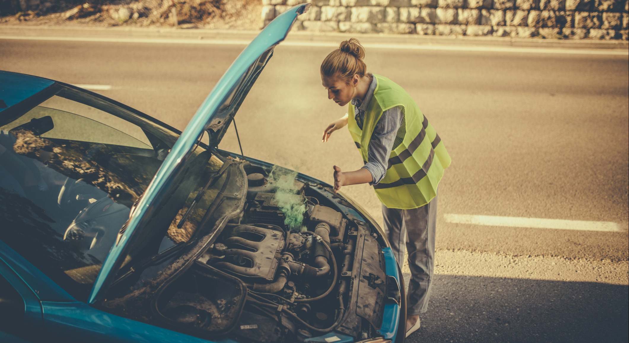 Conductora mirando el motor de su coche con el chaleco puesto