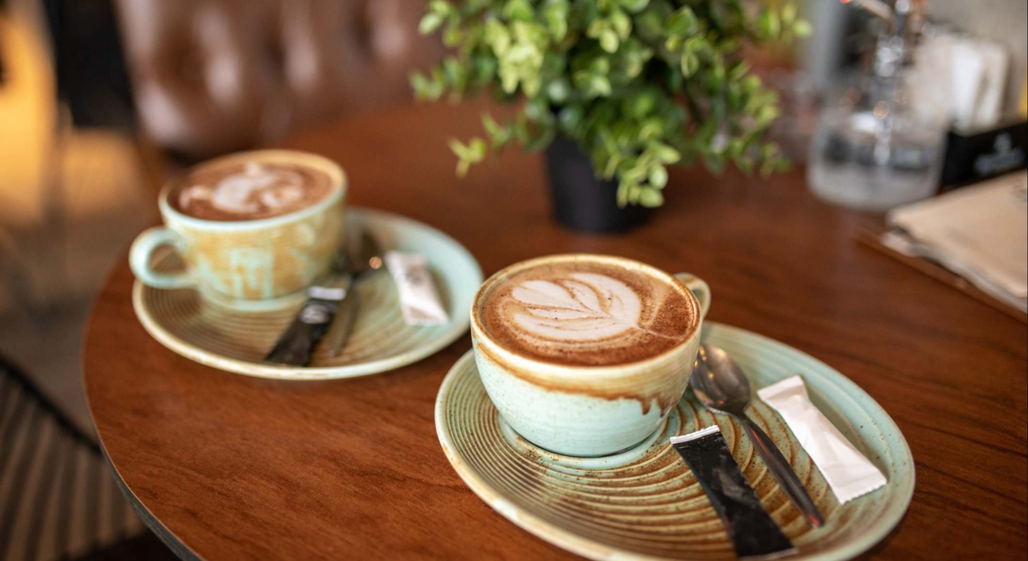 Dos tazas de café recién hecho con café con leche en una mesa de madera en la cafetería