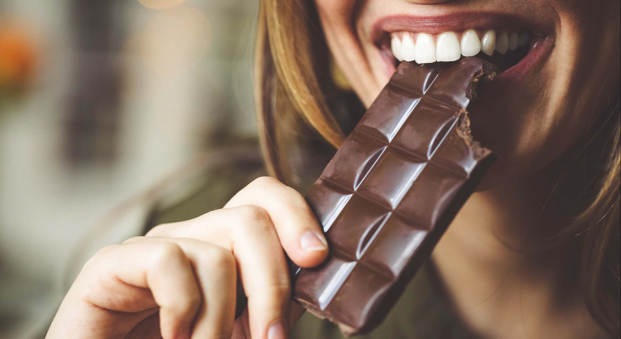 Mujer mordiendo una tableta de chocolate