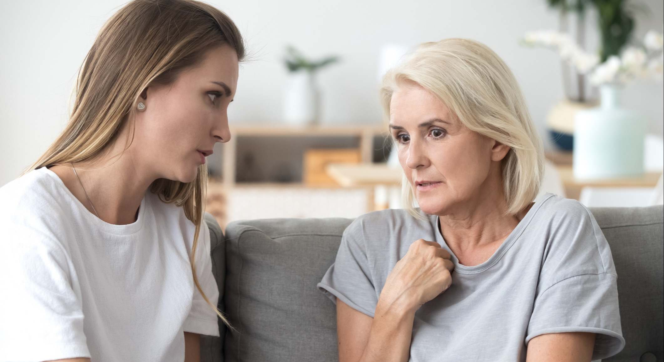 Madre e hija hablando en el sofá de una casa