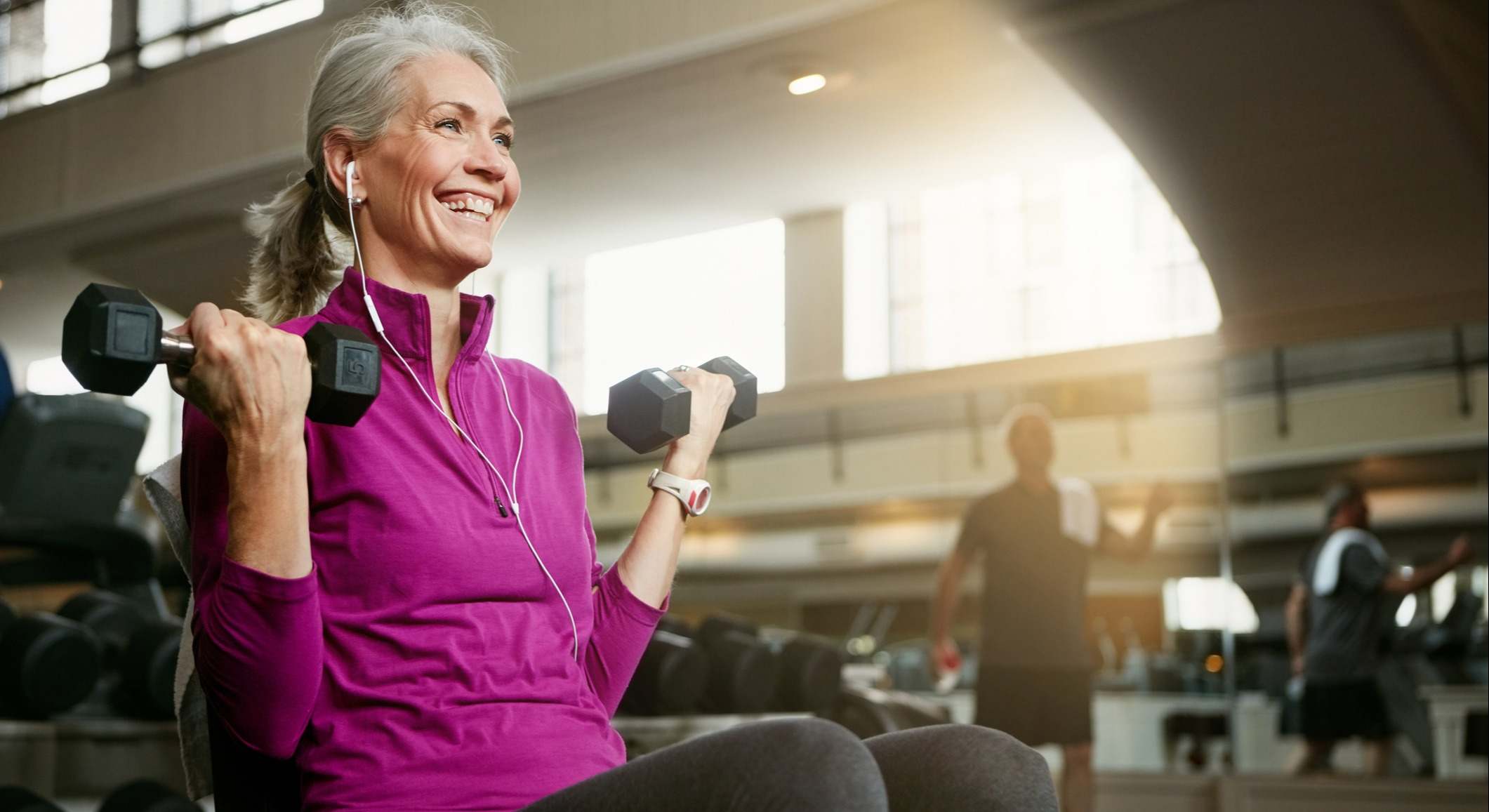 Mujer mayor levantando mancuernas en un gimnasio