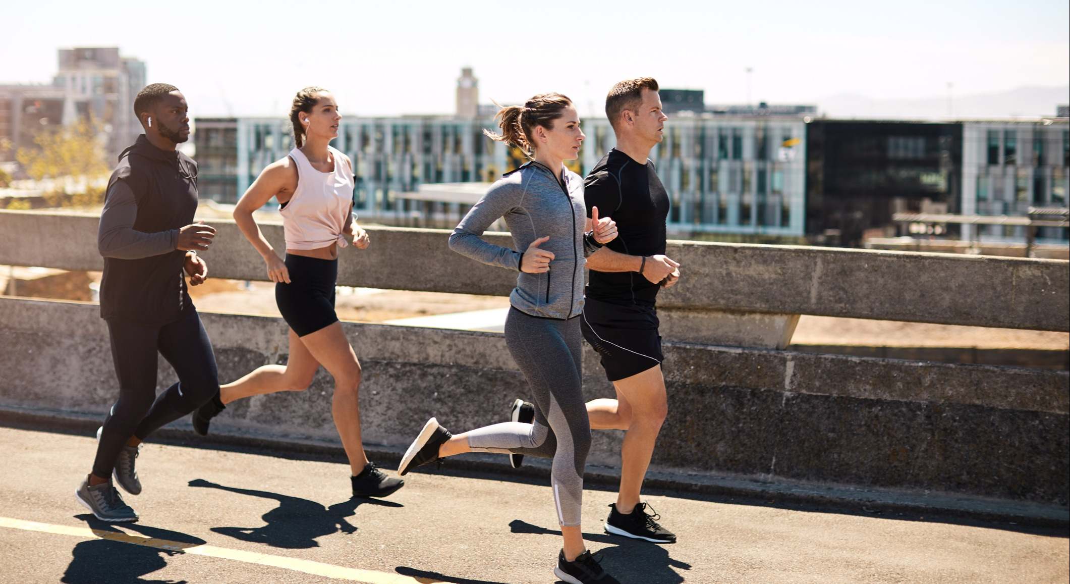 Dos mujeres y dos hombres corriendo en un entorno urbano