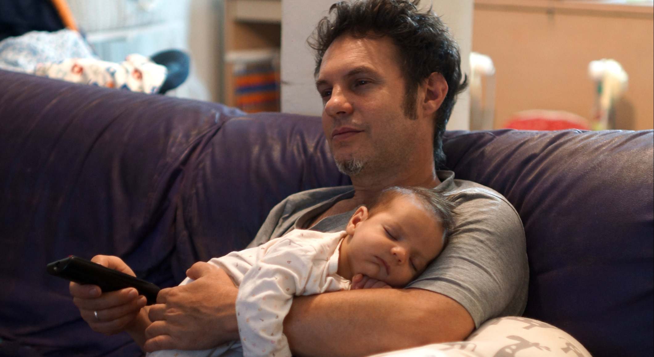 Padre viendo la televisión con su bebé en brazos. Foto: iStock