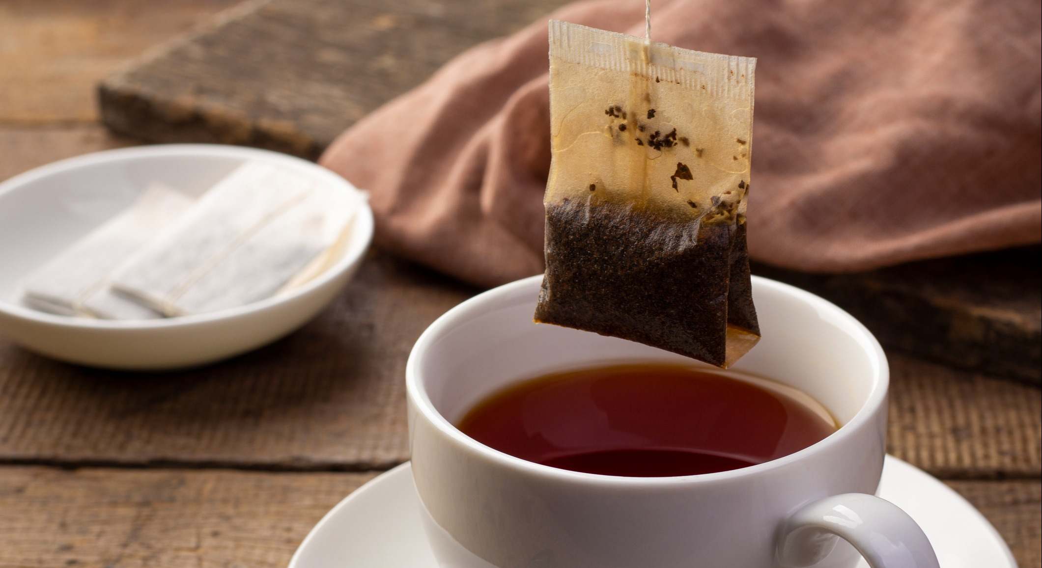 Bolsita de té encima de una taza sobre una mesa de madera