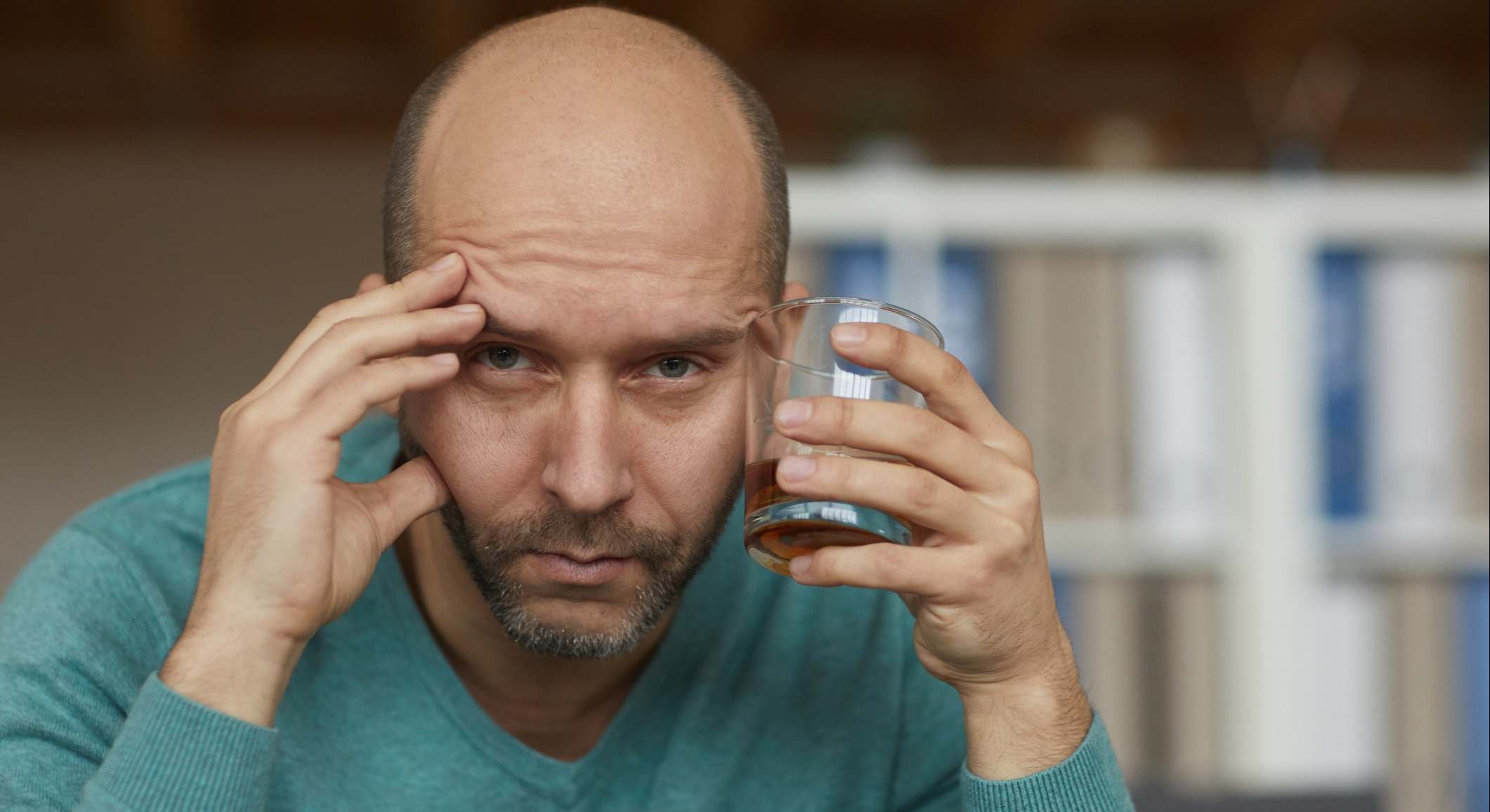 Hombre calvo con un vaso de alcohol