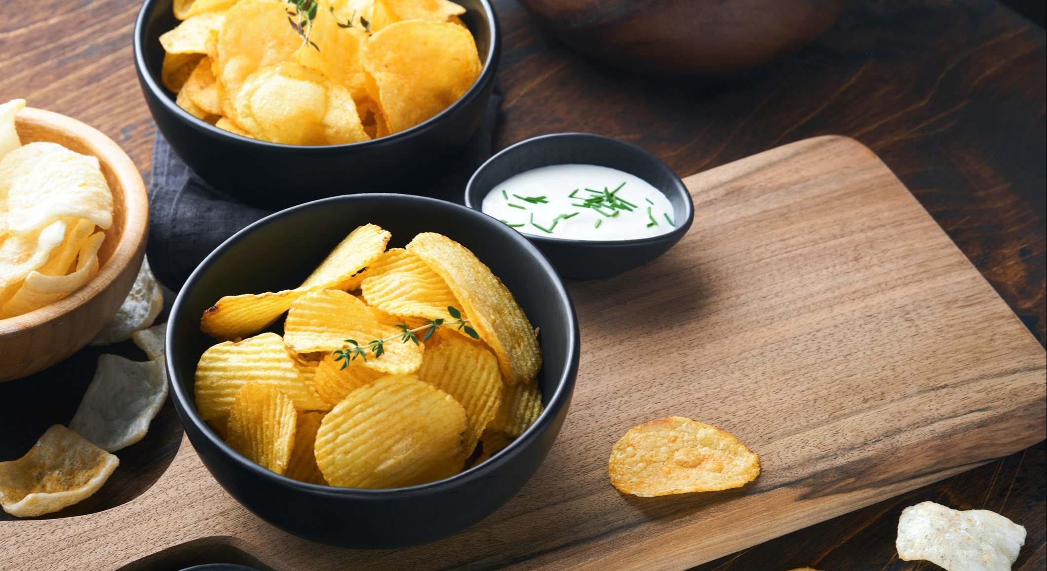 Patatas fritas en tazón de cerámica negro con salsa de crema agria y cebollas