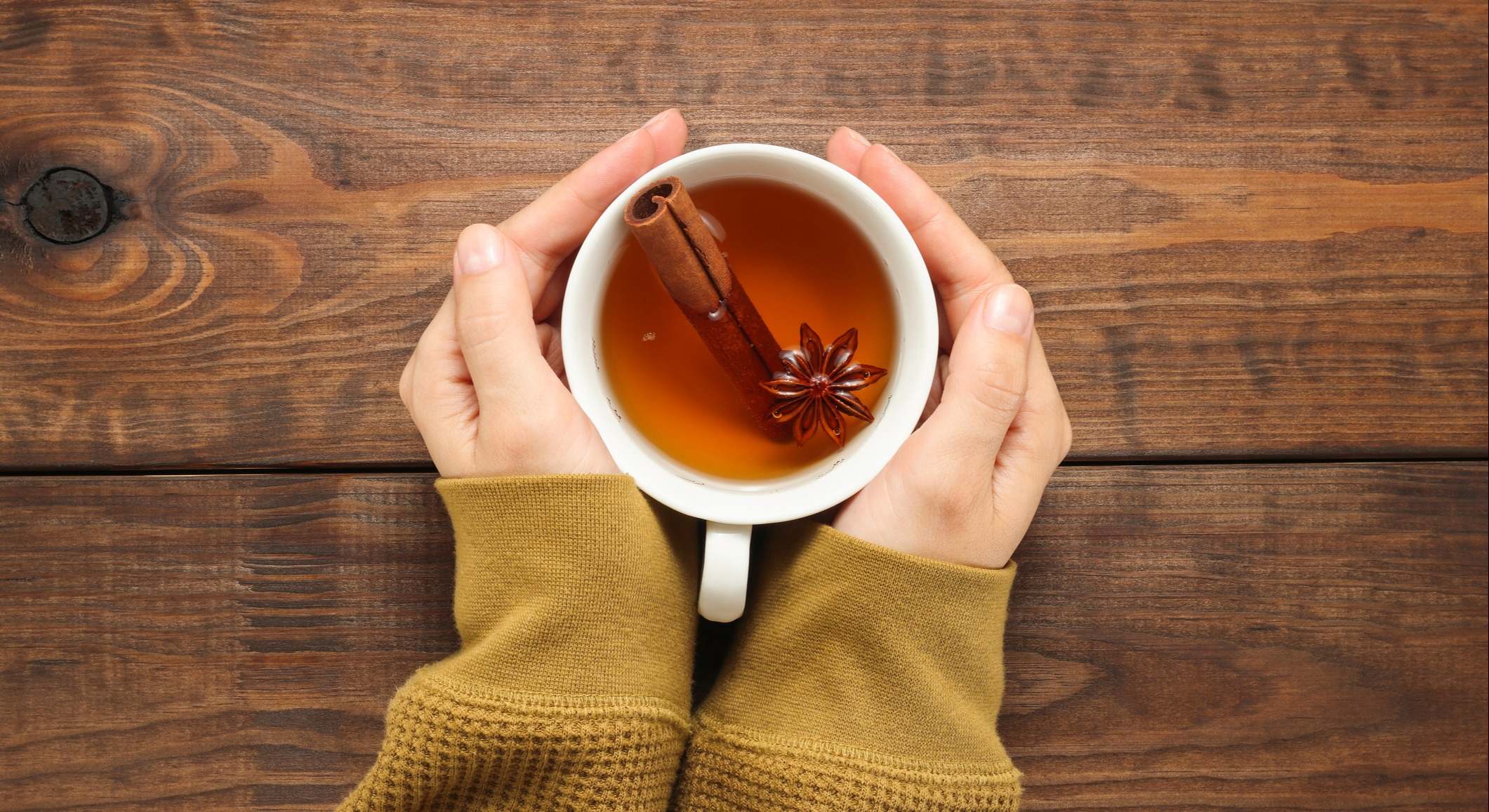 Manos sostienen una taza de té con especias, anís y canela