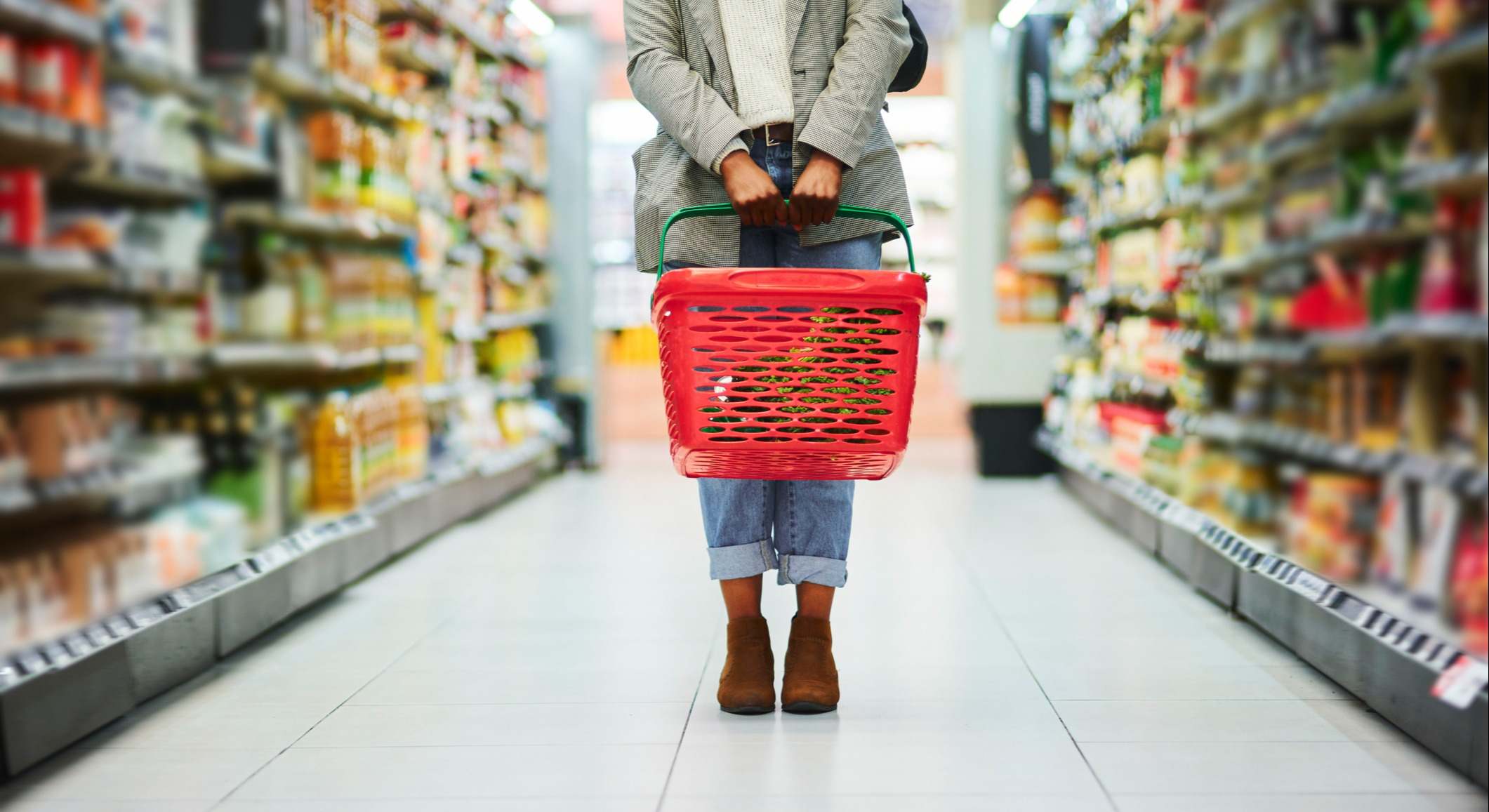 Mujer sujetando una cesta de la compra en un pasillo de un supermercado
