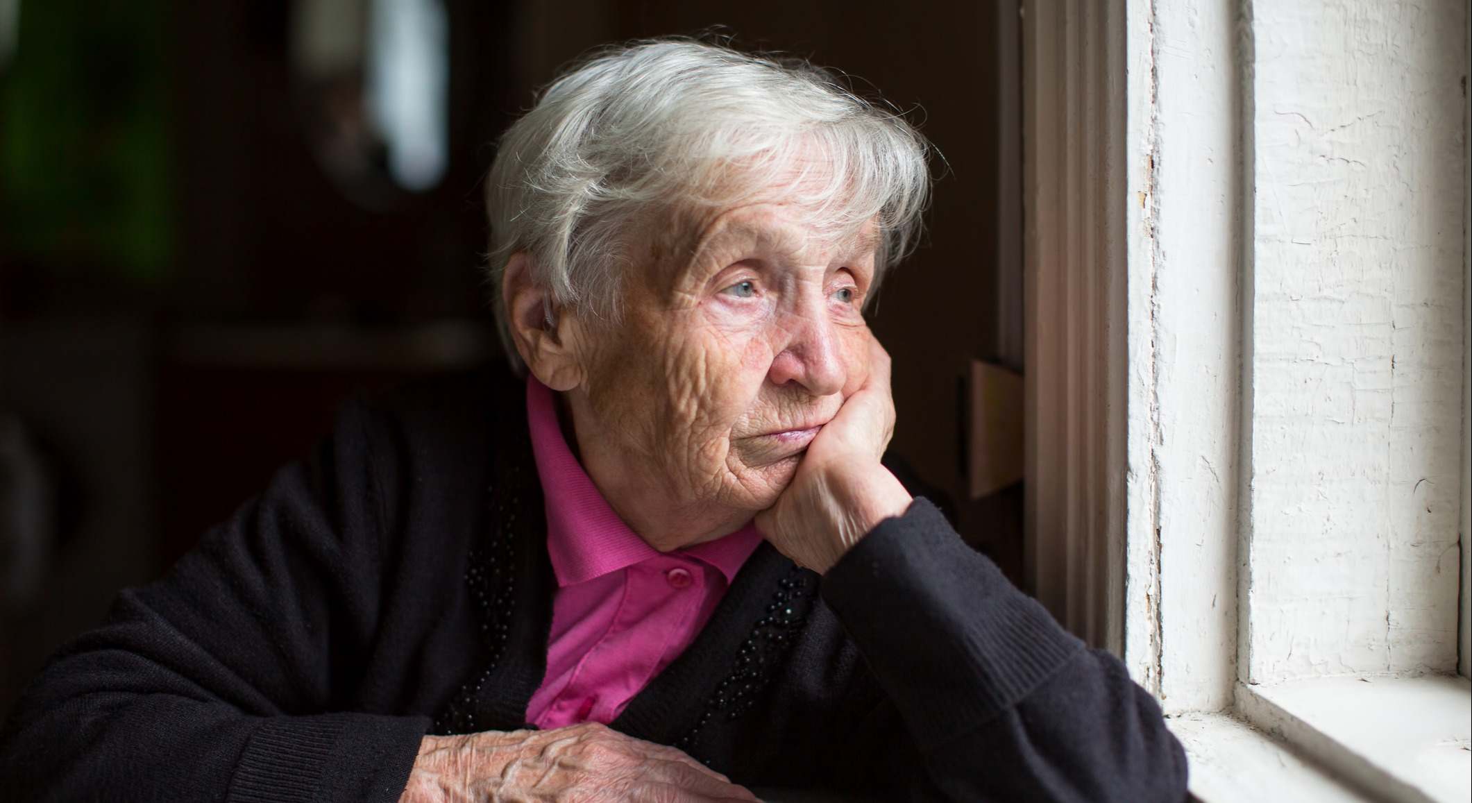 Una anciana tristemente mirando por la ventana