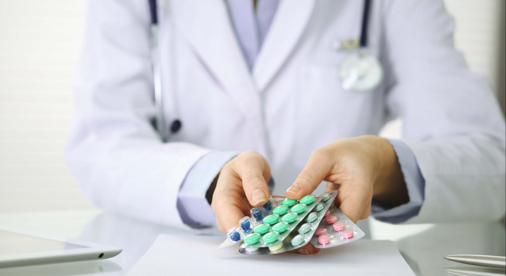 Manos de un doctor sosteniendo paquete de diferentes medicamentos