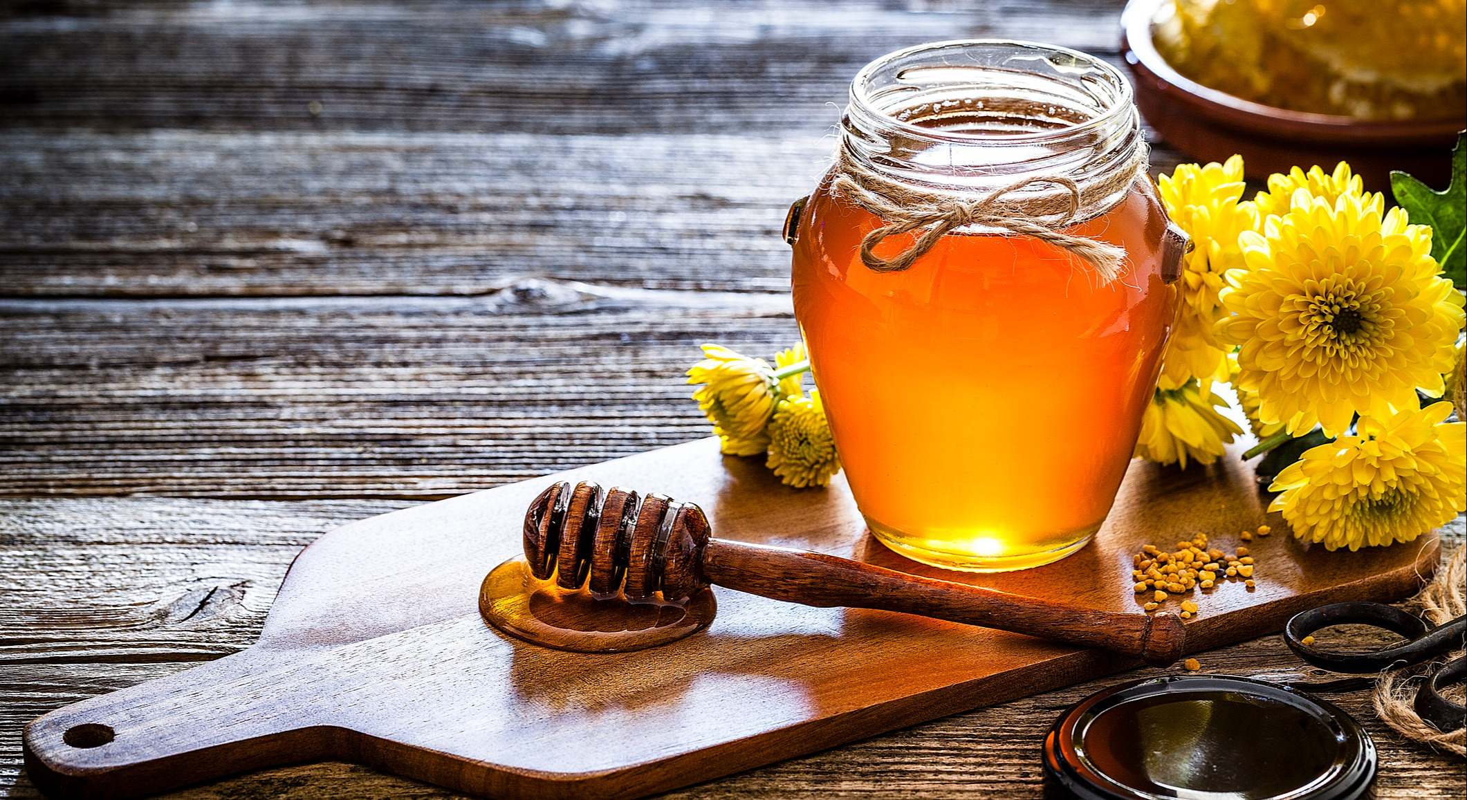 Tarro de miel con el cazo de la miel en mesa de madera rústica