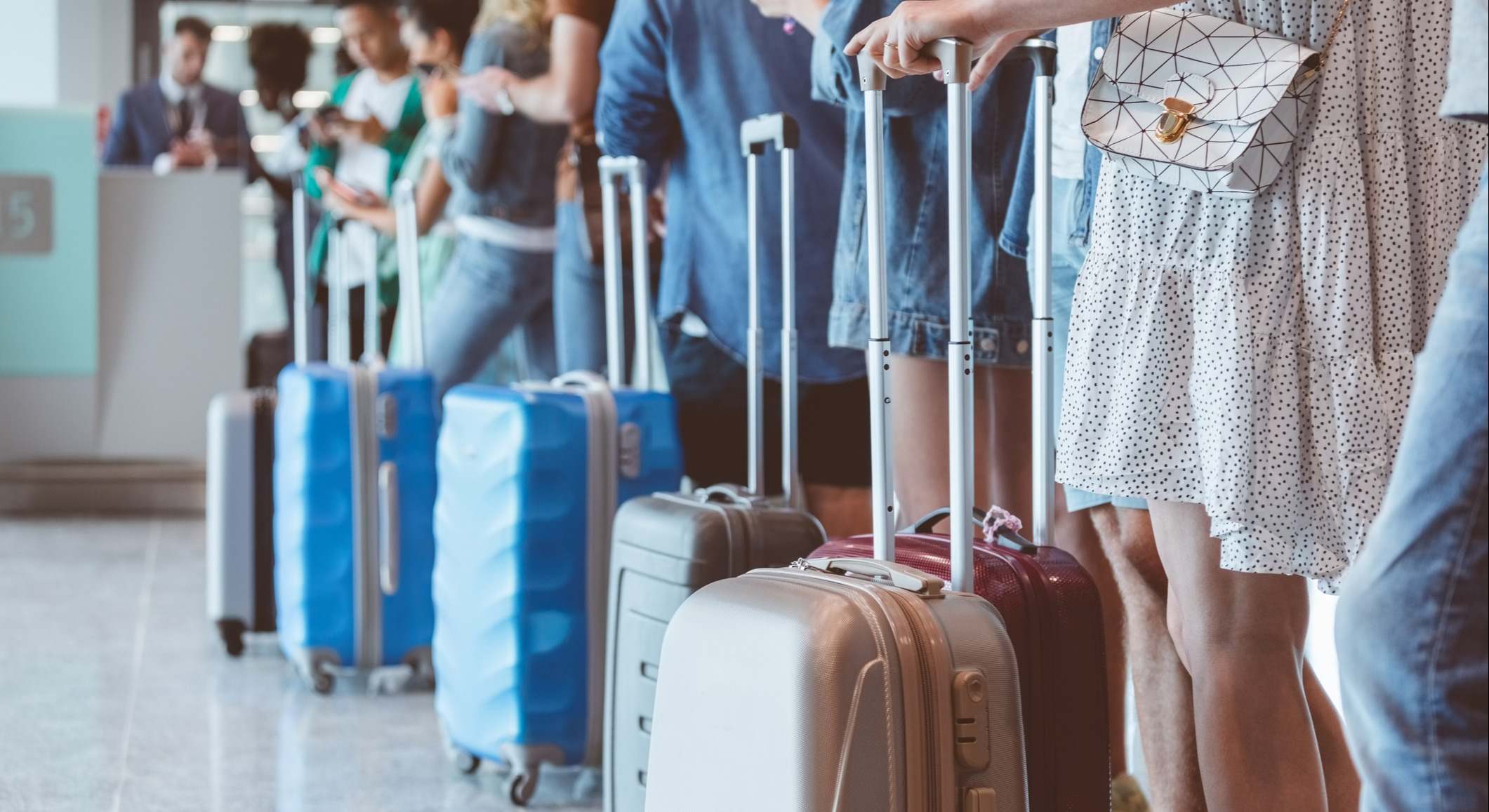 Pasajeros con equipaje esperando en la fila del aeropuerto