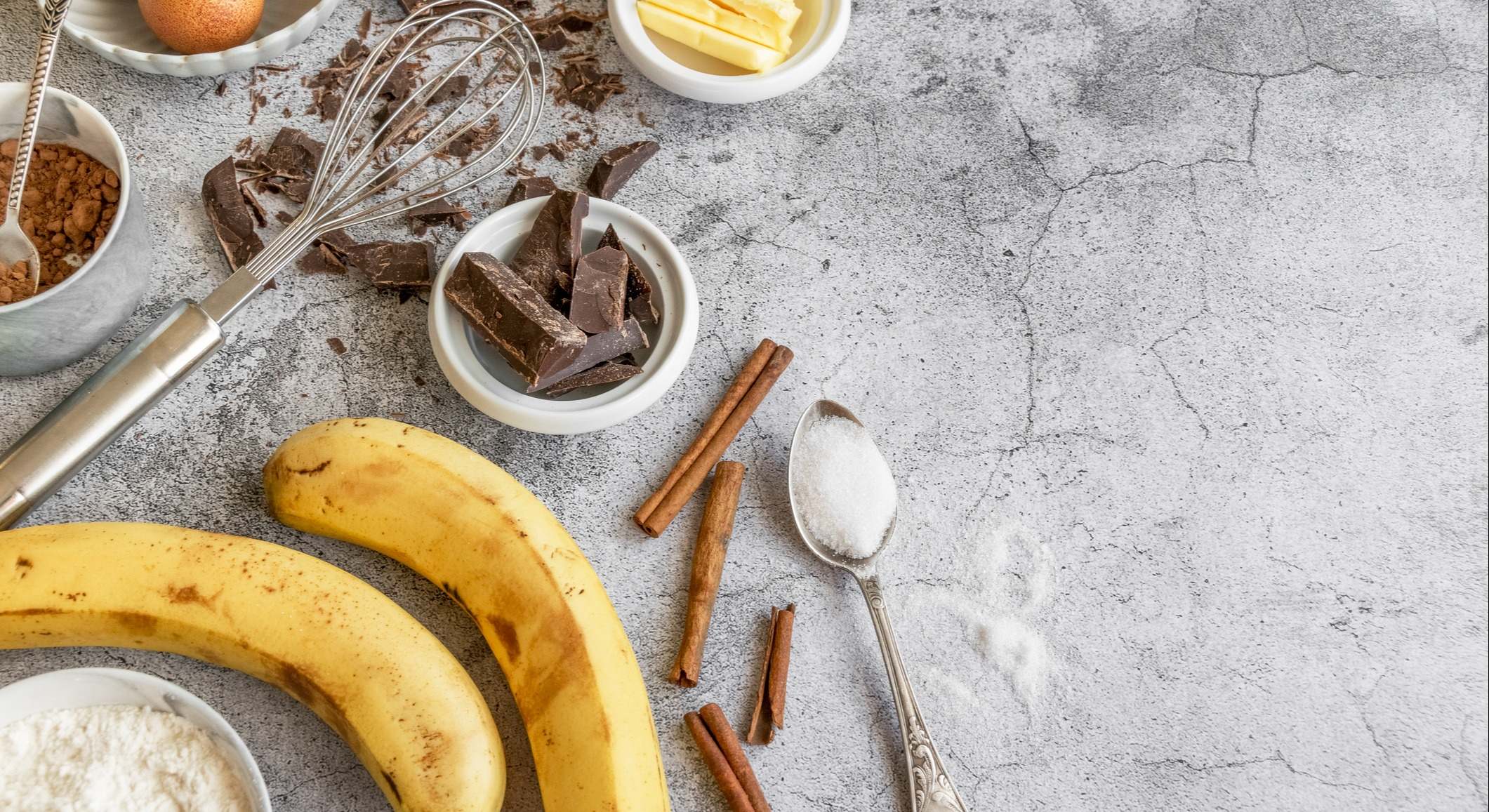 Plátanos, chocolate, canela, azúcar y utensilios sobre una mesa