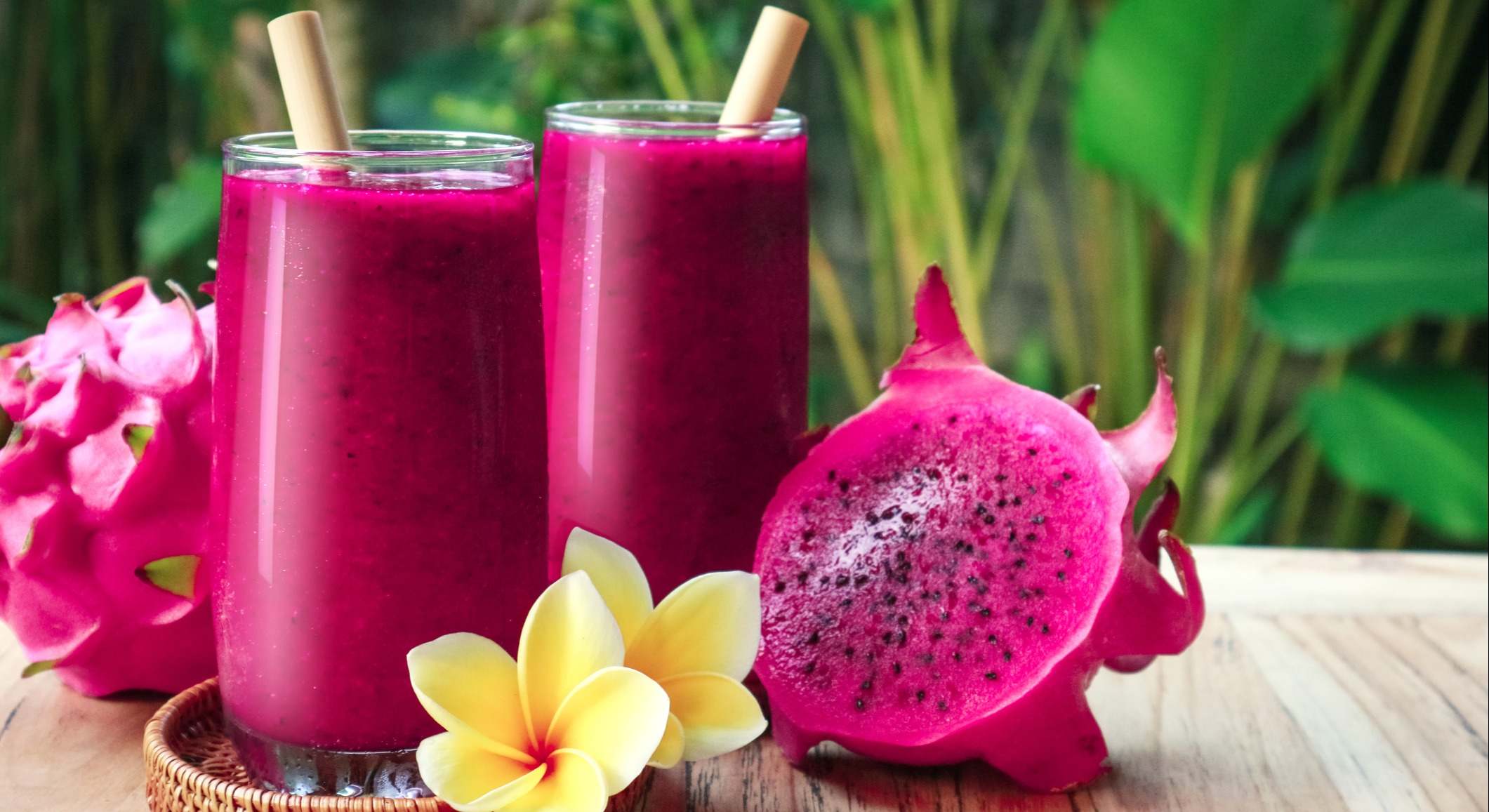 Dos vasos con zumo de fruta de pitaya sobre una mesa de madera