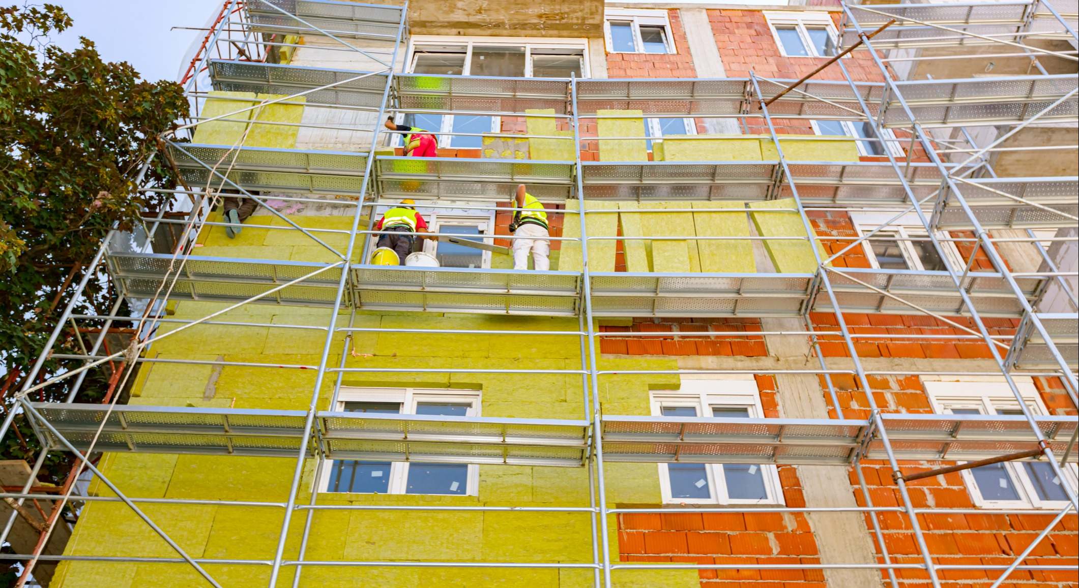 Trabajadores en andamios instalando lana de roca en la fachada de un edificio