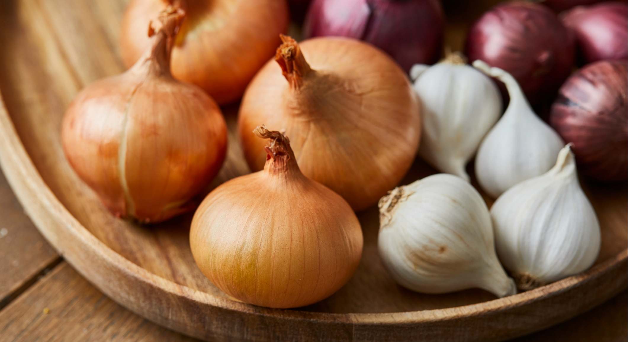 Ajo, cebolla y cebolla roja española en un plato de madera