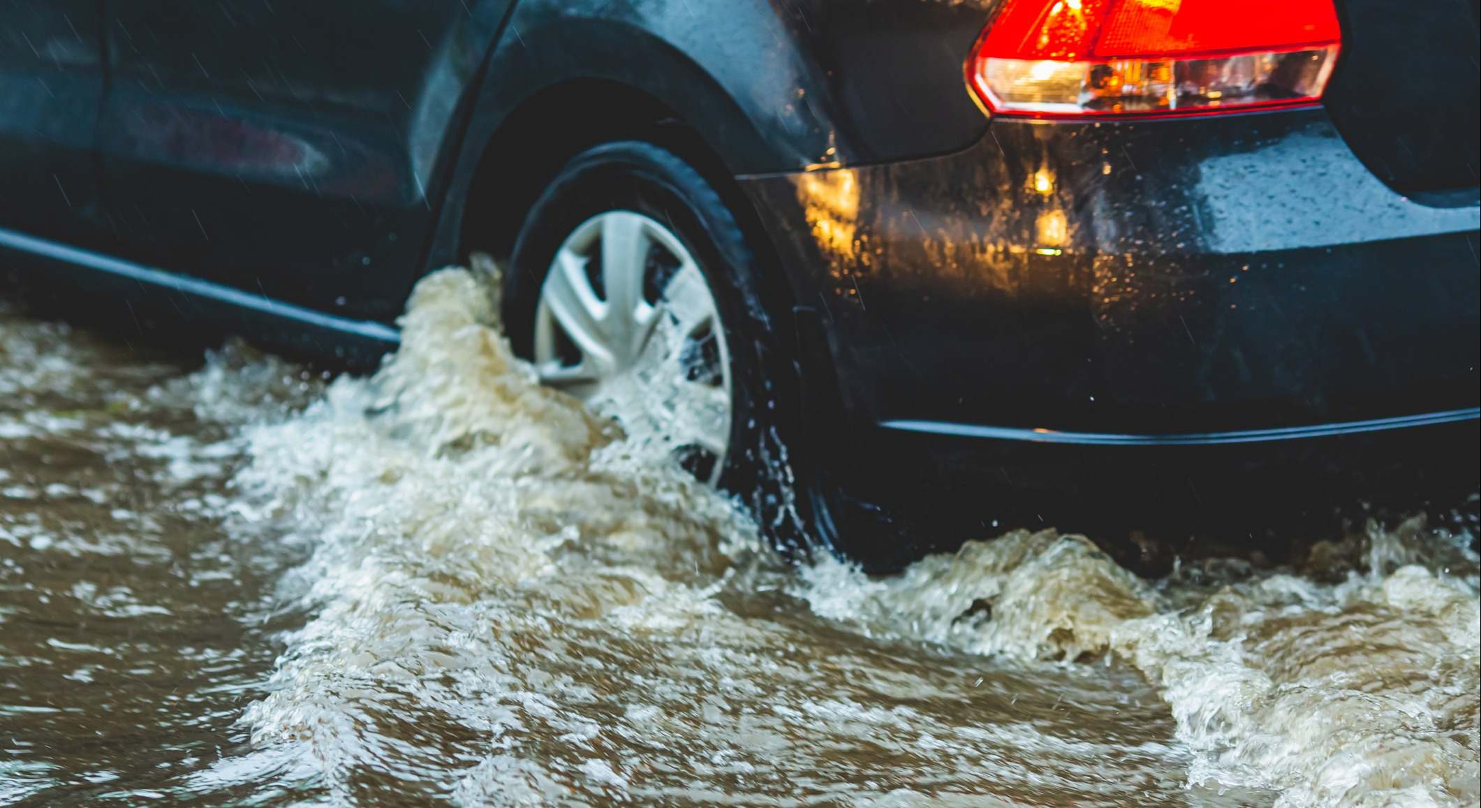 Coche circulando sobre carretera inundada