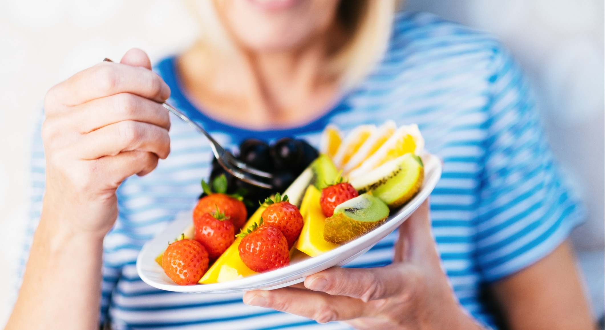Mujer comiendo un plato con varios frutas