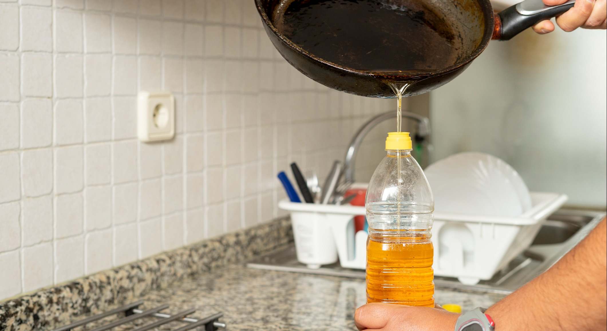 Aceite reciclado de una sartén en una botella de plástico en la cocina de su casa