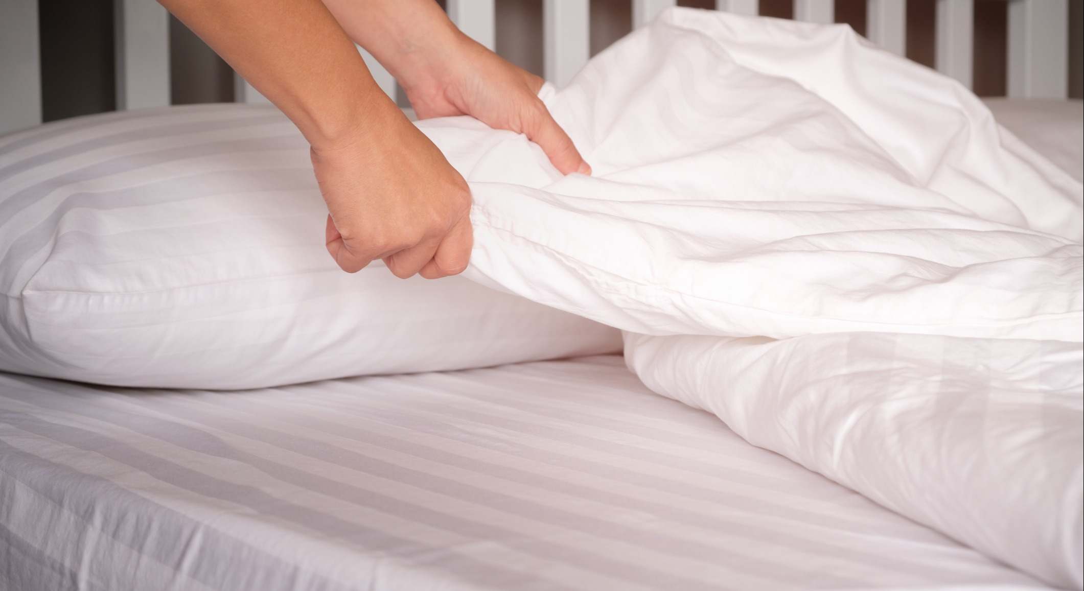 Las manos de una persona que están cambiando sábanas de una cama