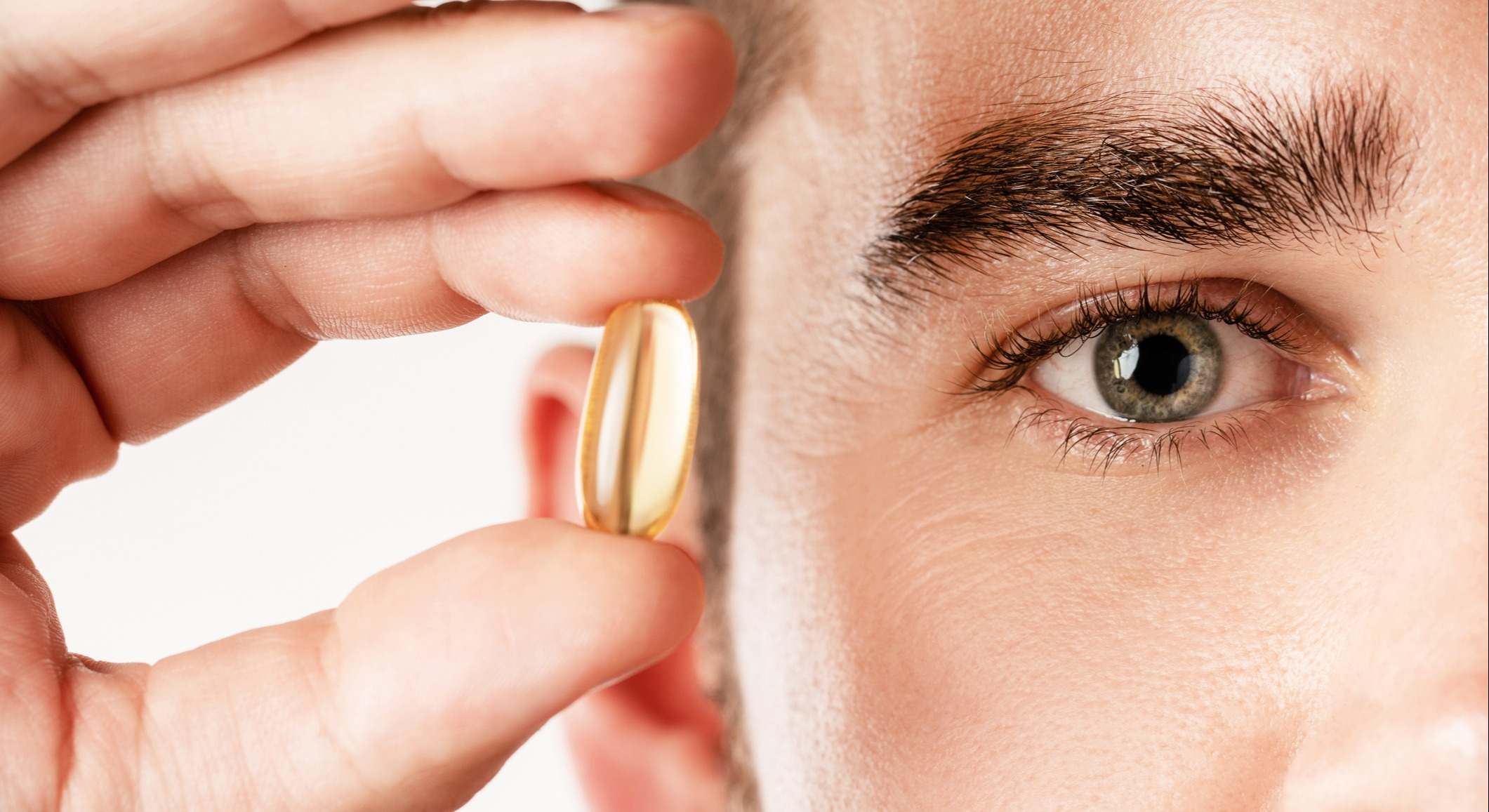 Hombre sosteniendo una vitamina con un primer plano de su ojo