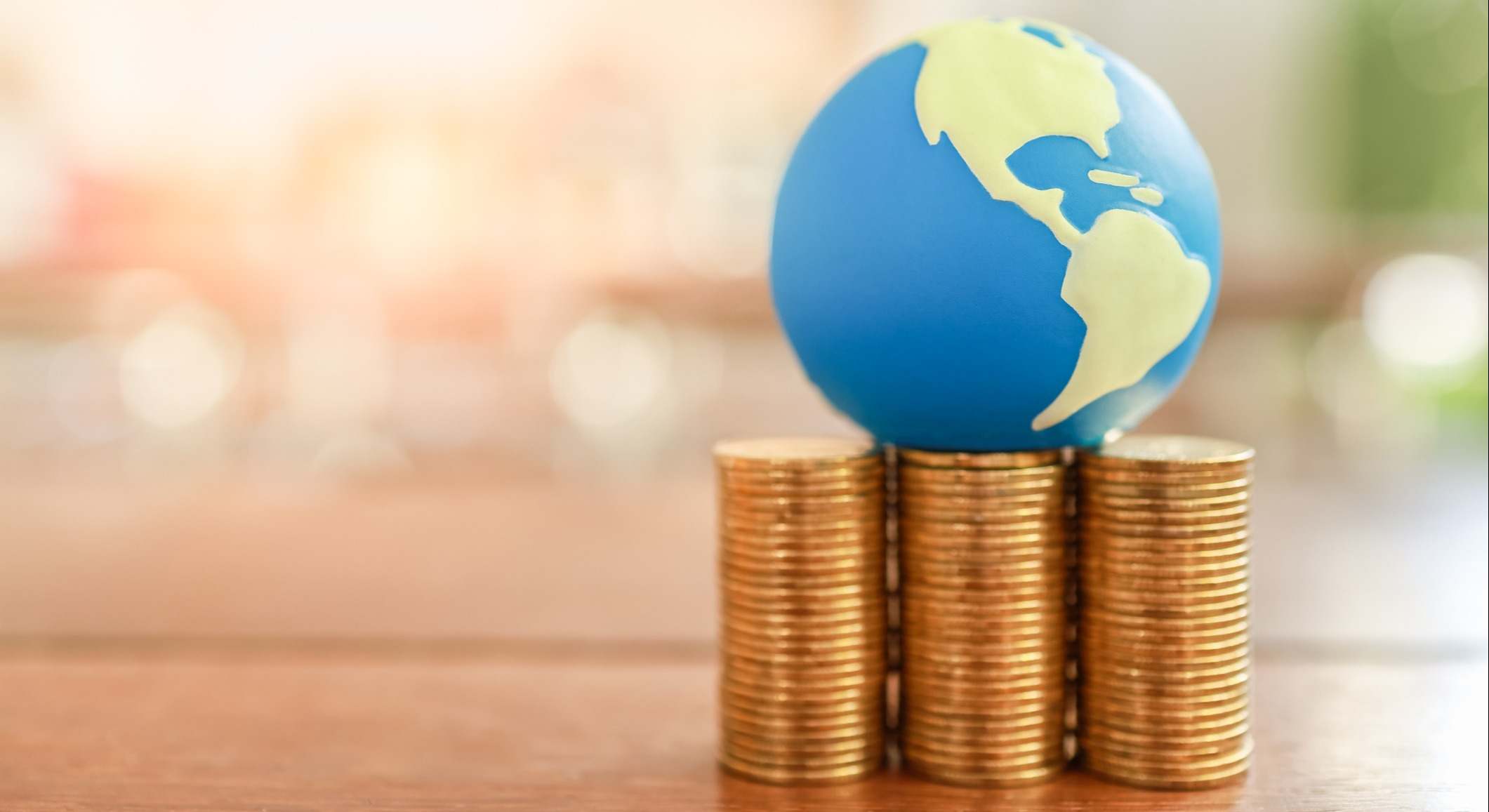 Bola del mundo sobre un montón de monedas. Imagen: iStock.