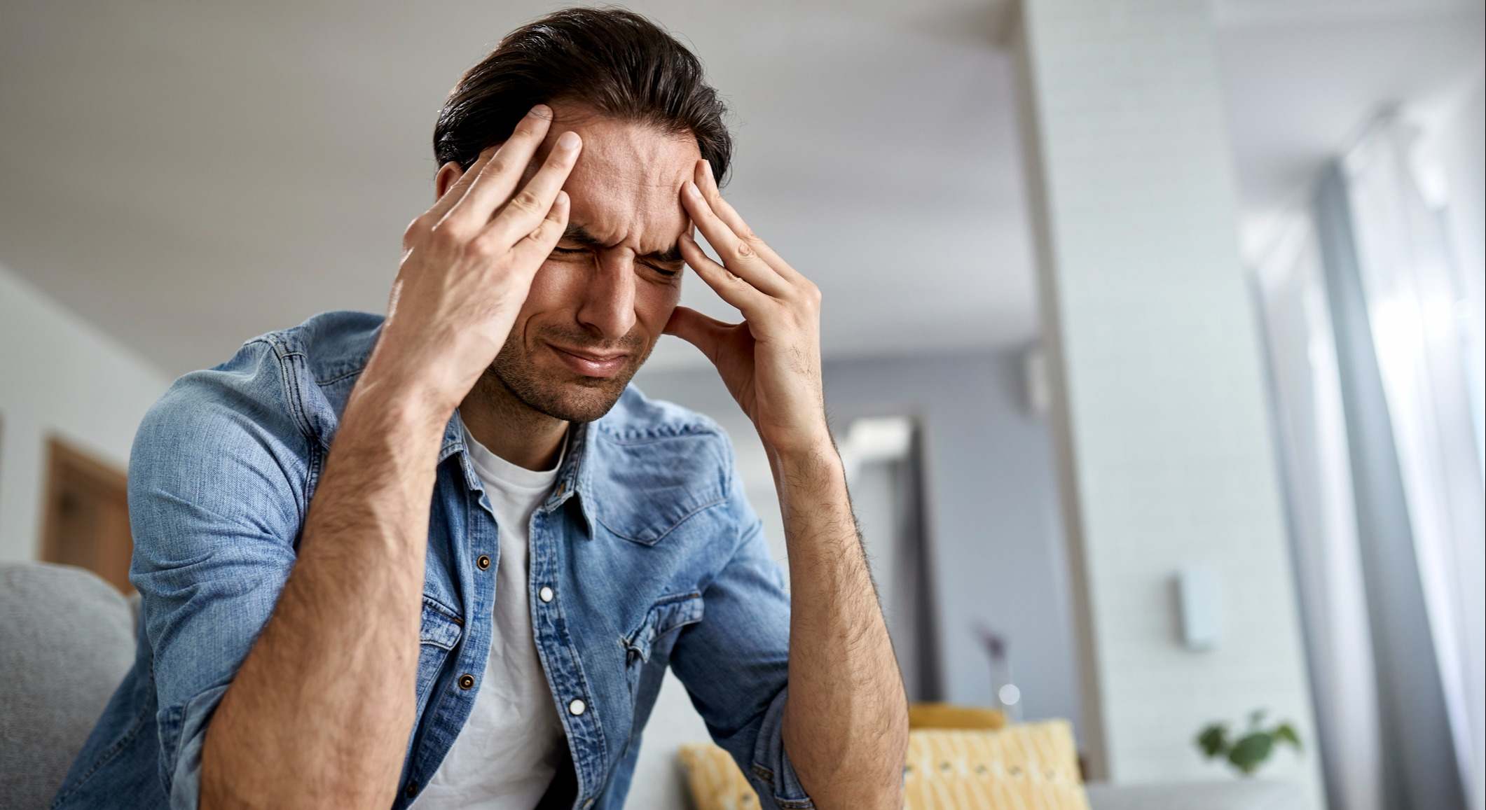 Hombre que tiene dolor de cabeza mientras está en casa