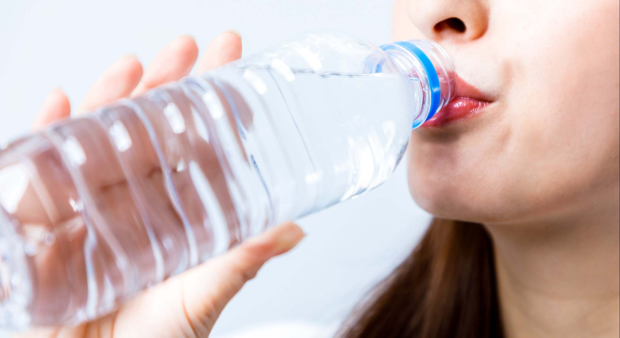 Una mujer joven bebiendo una botella de agua de plástico