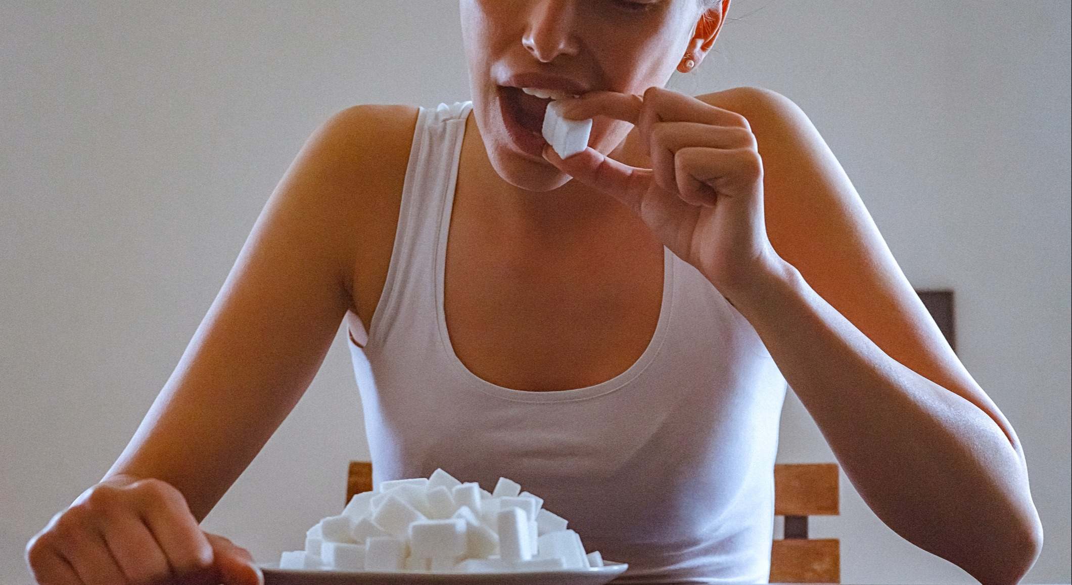 Primer plano de una mujer joven comiendo terrones de azúcar