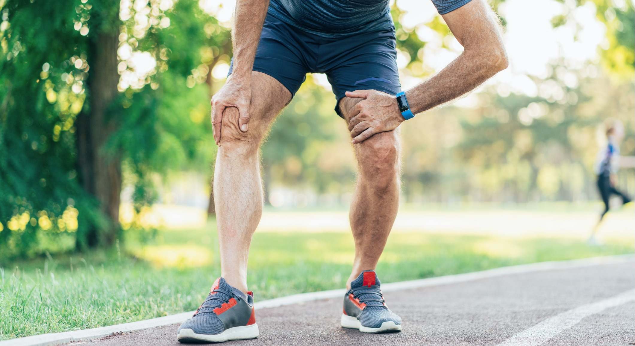 Hombre con dolor en la rodilla mientras hace ejercicio en un parque